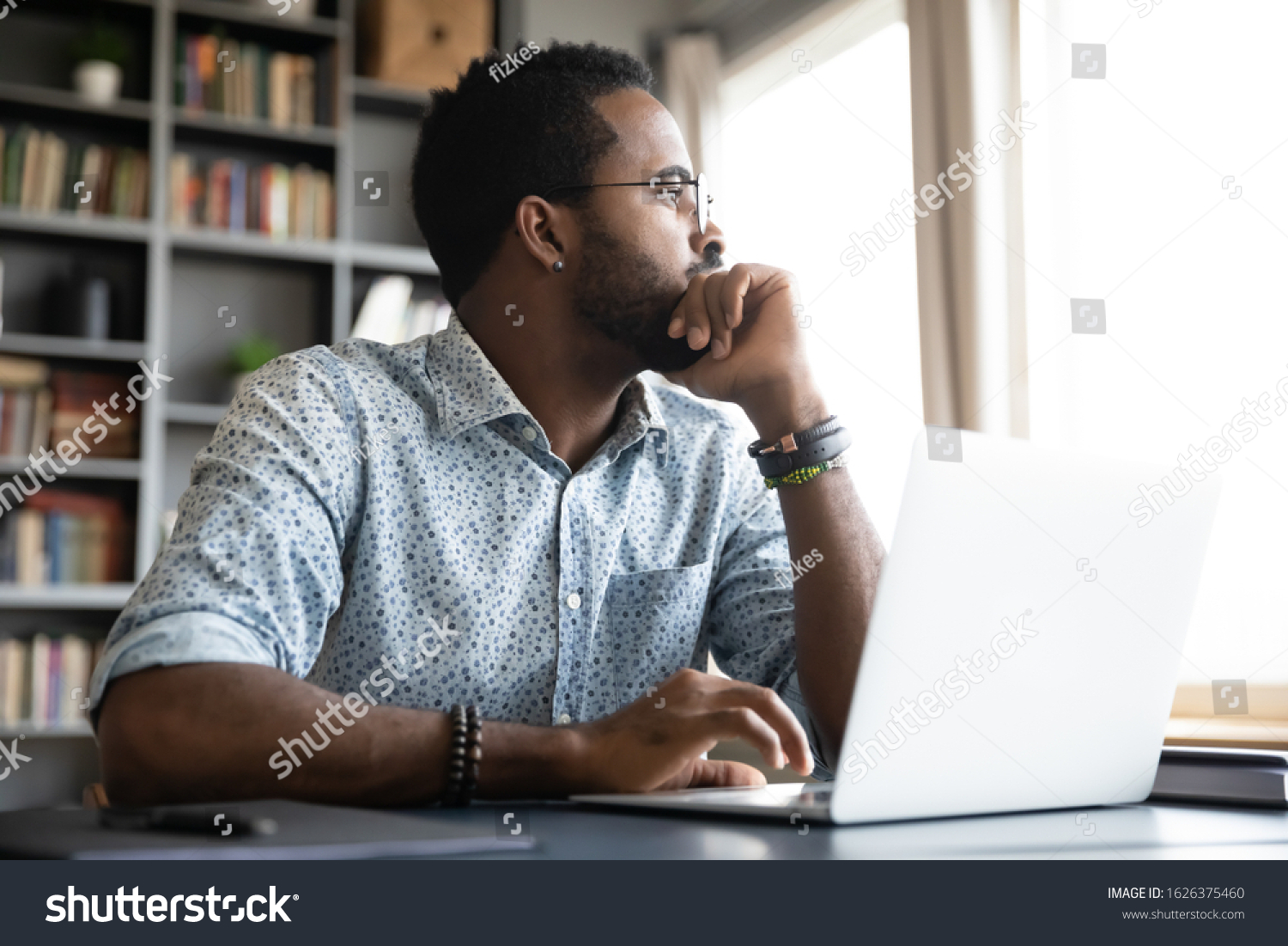 Thoughtful serious african professional business man sit with laptop thinking of difficult project challenge looking for problem solution searching creative ideas lost in thoughts at home office desk #1626375460