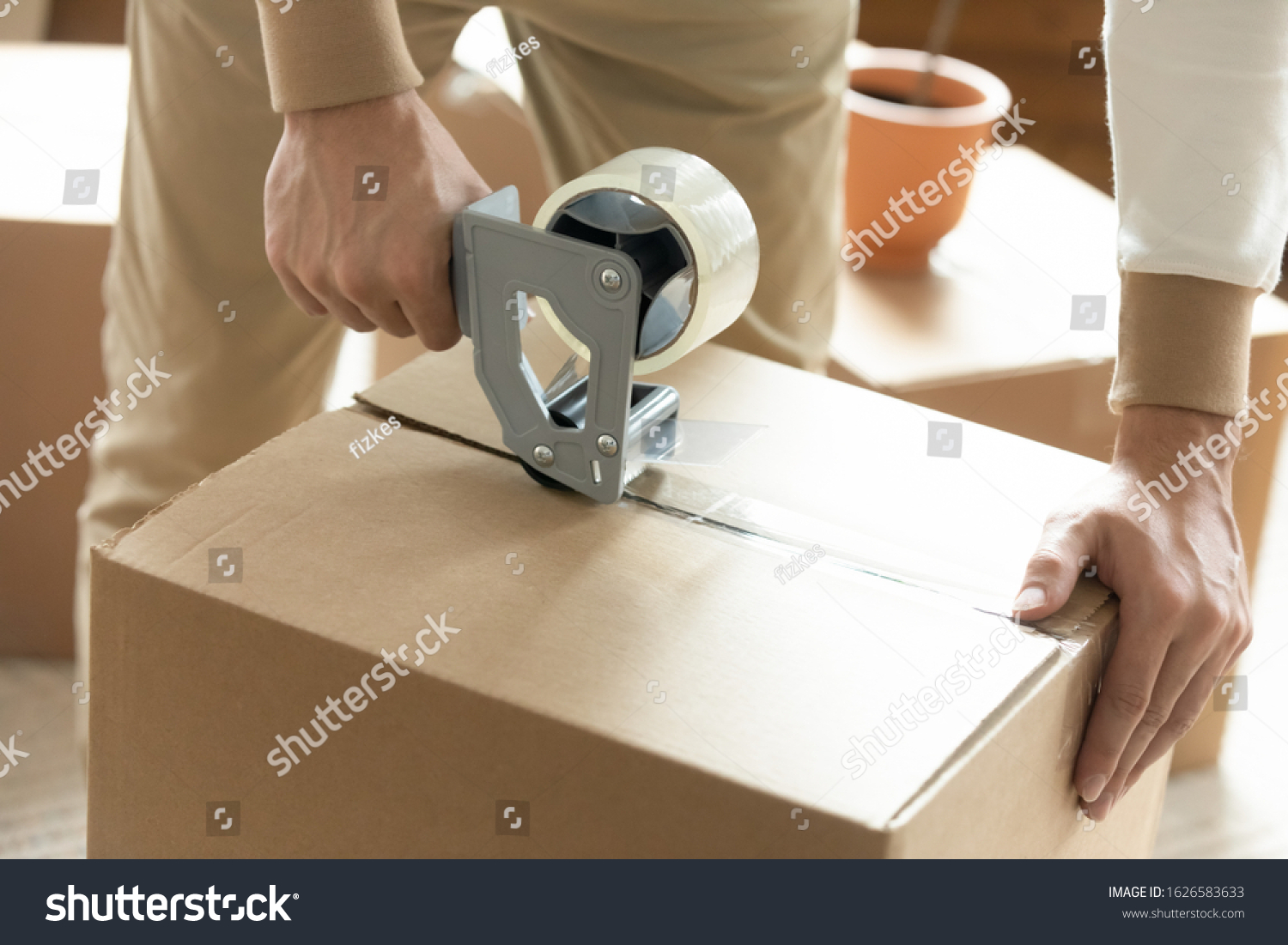 Close up of man sealing packing cardboard box with scotch tape moving or relocating, Caucasian husband roll carton package personal belongings using adhesive cellotape, relocation service concept #1626583633