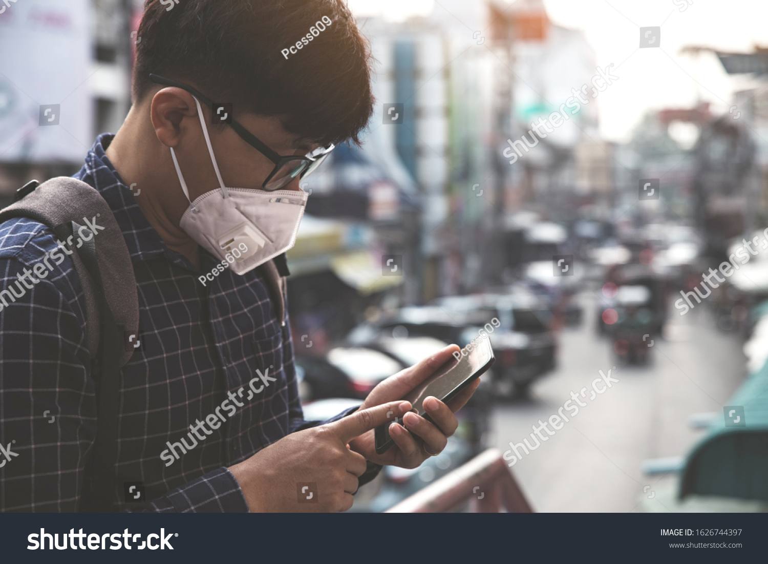Concept of coronavirus quarantine. MERS-Cov, Novel coronavirus (2019-nCoV), man with medical face mask using the phone to search for news.Air pollution  #1626744397