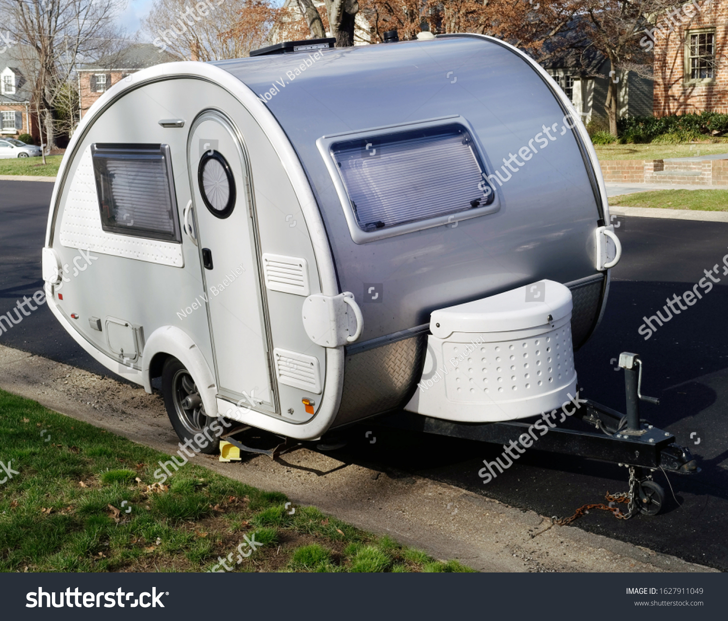Cute teardrop shaped camping trailer parked in residential neighborhood. #1627911049