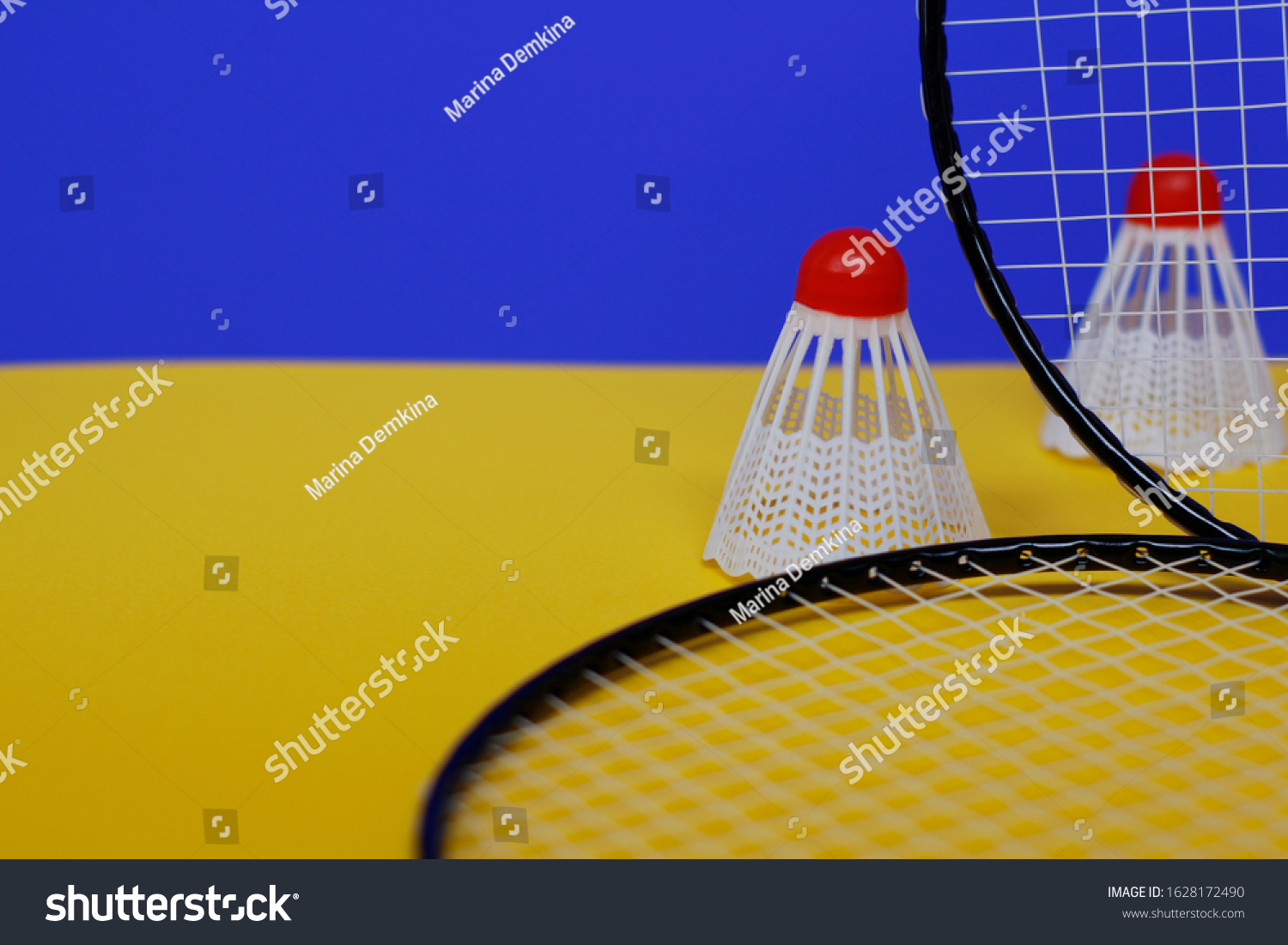 Badminton. Two shuttlecocks and two badminton racket. The colored background is blue and yellow. Idea for a magazine. #1628172490