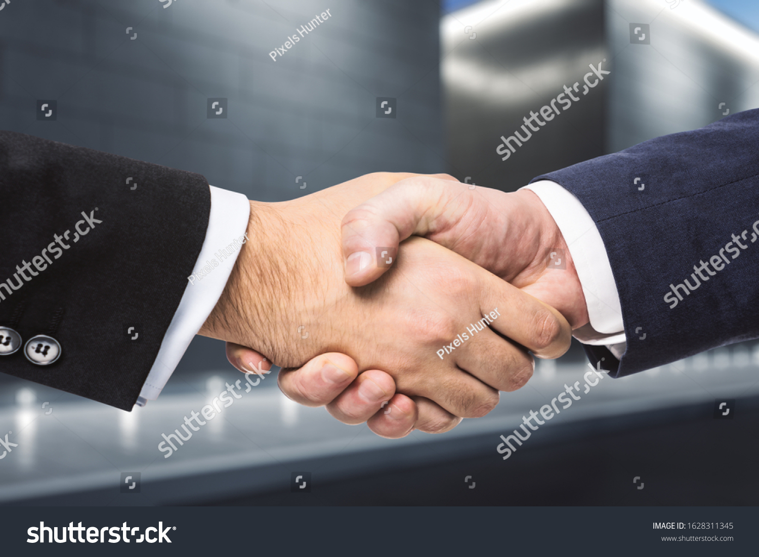 Two businessmen shake hands in the evening on a abstract exterior backgrond. Insider concept #1628311345