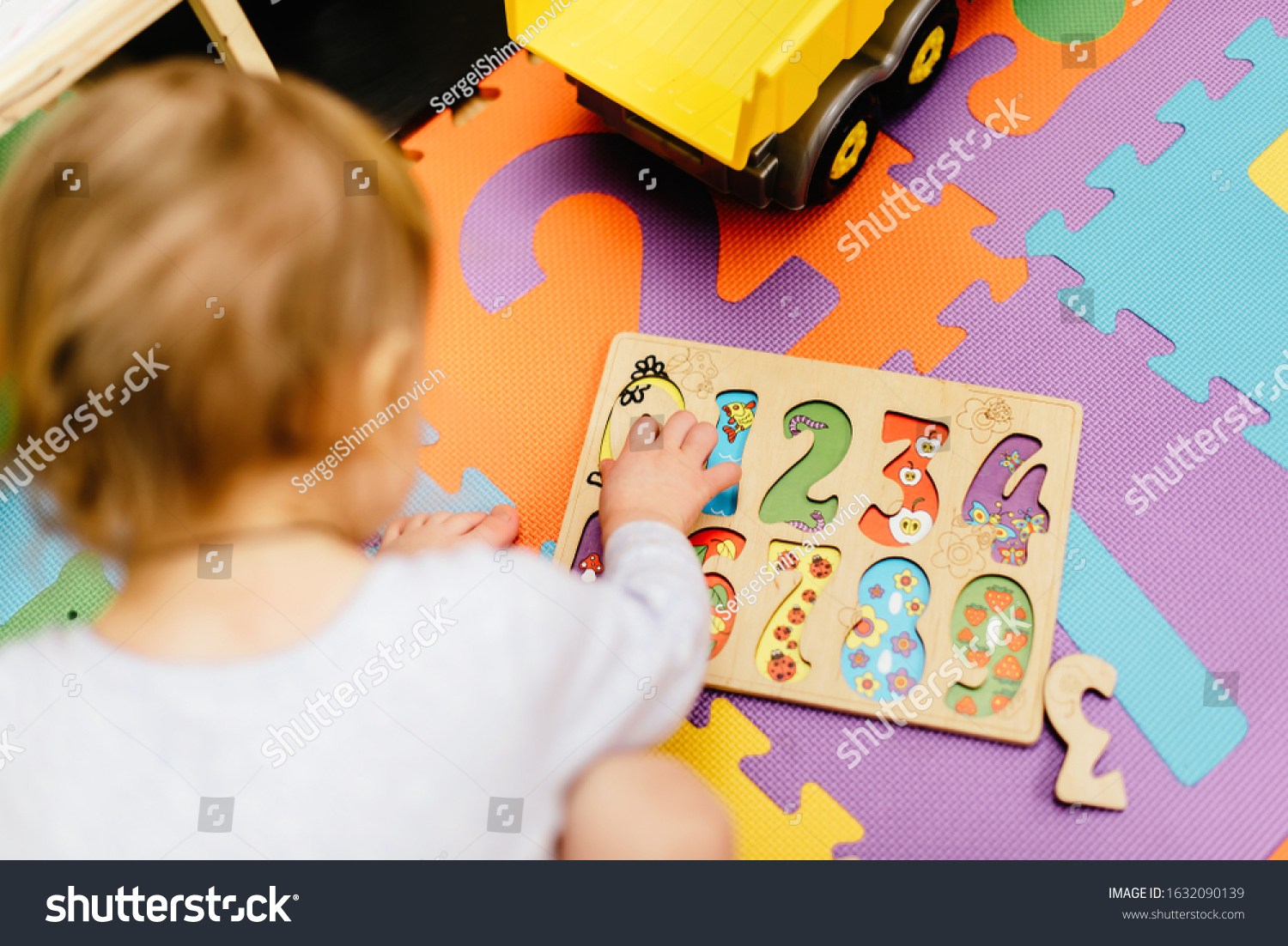 child on the carpet collects a puzzle of numbers, learns to count and learns numbers. Concept of learning by playing for toddler development #1632090139