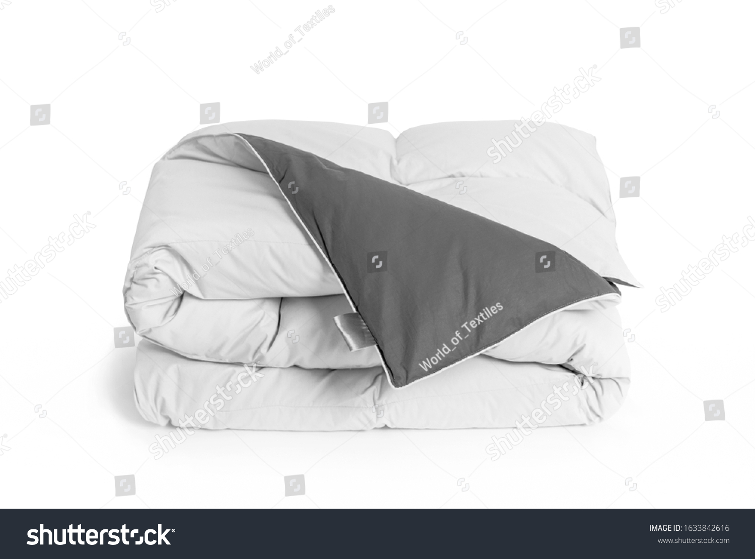 Folded soft white duvet, blanket or bedspread with the gray back side and empty white label, against white background. Close up photo #1633842616