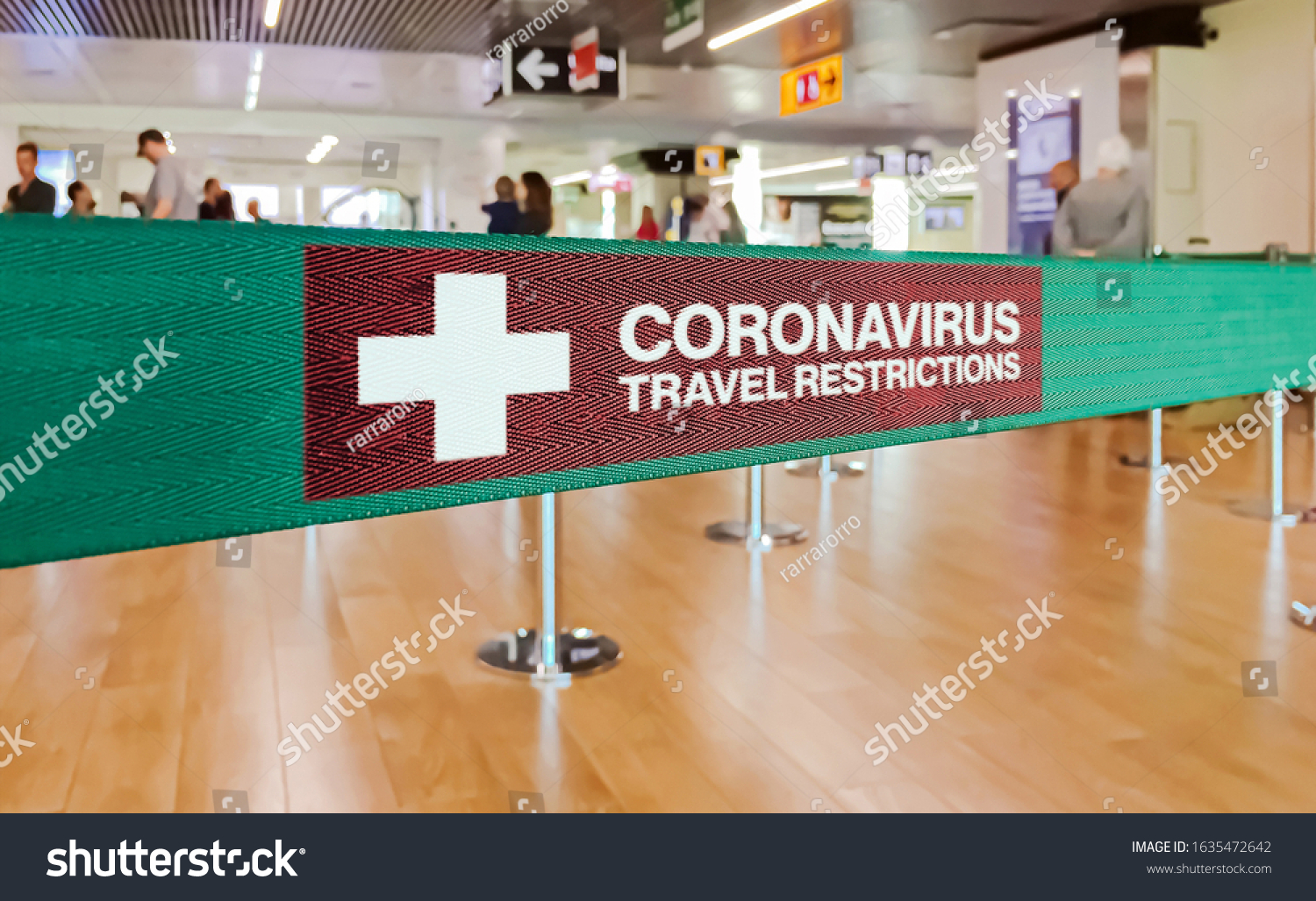 Green ribbon barrier inside an airport with the warning of travel restrictions due to the spread of the dangerous Coronavirus #1635472642