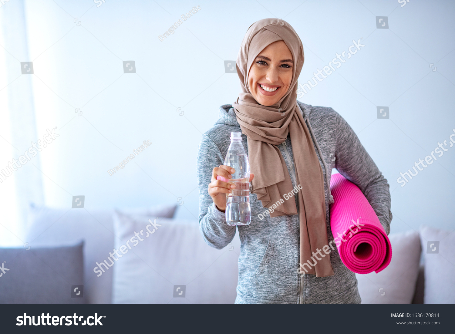 Fit young muslim woman drinking water . Young muslim woman ready to running. Young muslim woman holding bottle of water and fitnes mate. Portrait of muslim woman likes her active life.



 #1636170814