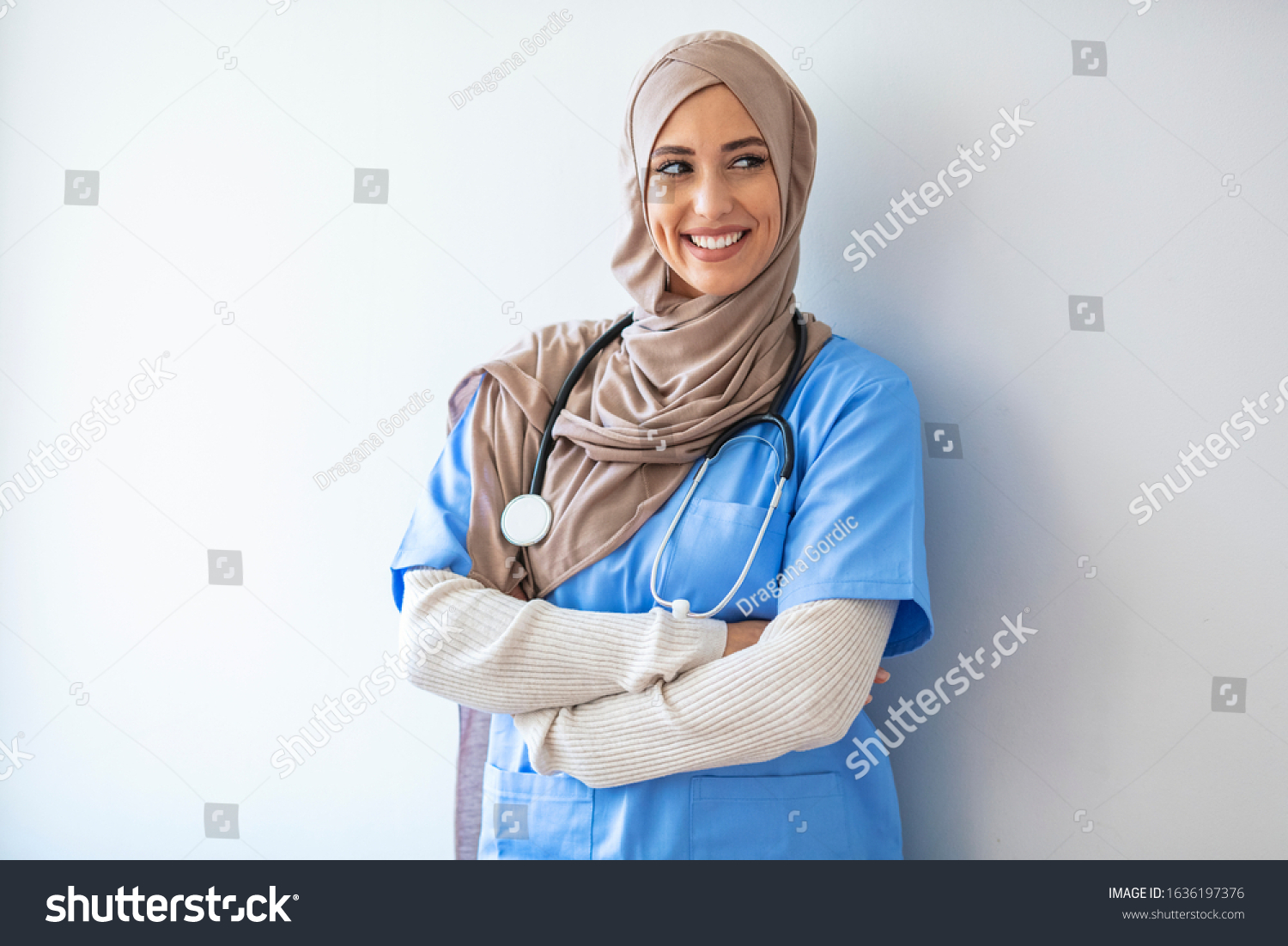 Arab nurse woman wearing hijab over isolated background looking away to side with smile on face, natural expression. Laughing confident. Authentic Confident Middle Eastern Healthcare Worker #1636197376