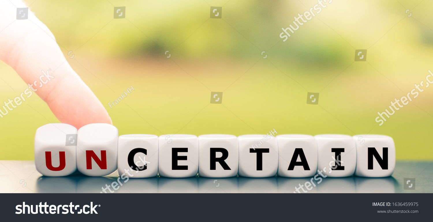 Hand turns dice and changes the word "uncertain" to "certain". #1636459975