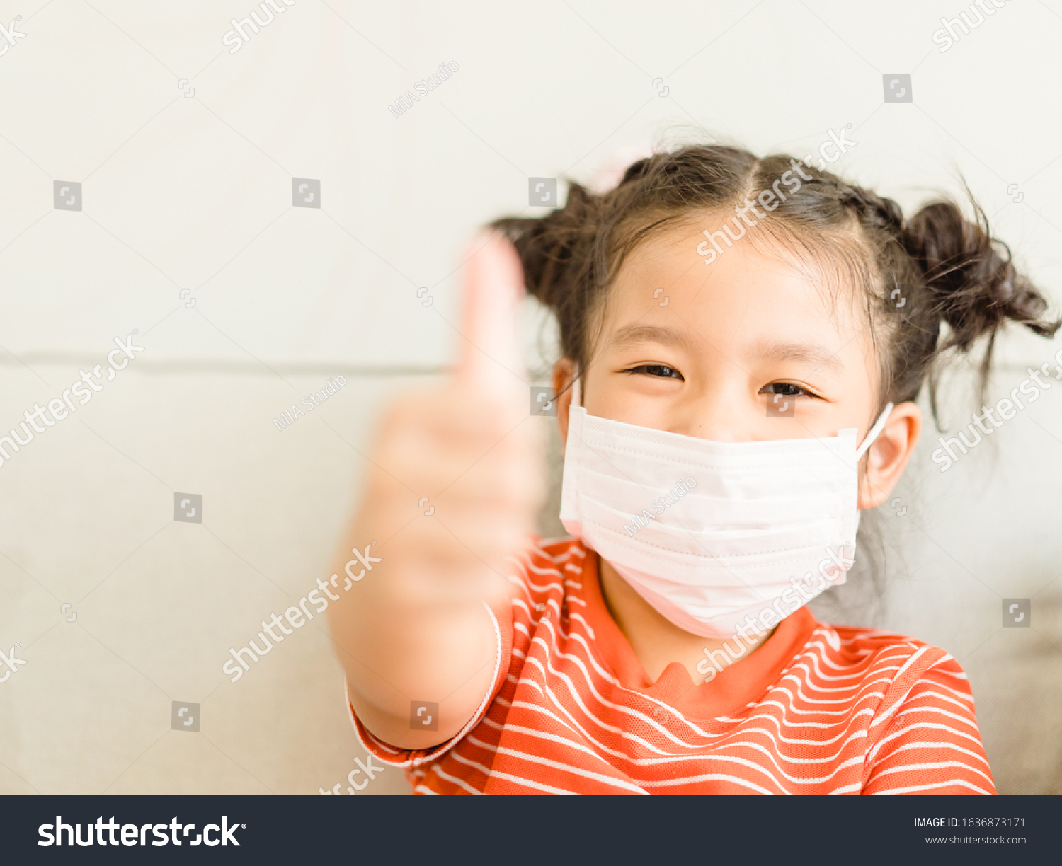 Coronavirus Covid-19.Online education.Little asian kid girl wearing face mask show thumbs up for Thank you doctor, Happy at home. Covid-19 coronavirus.Stay home.Social distancing.New normal behavior. #1636873171