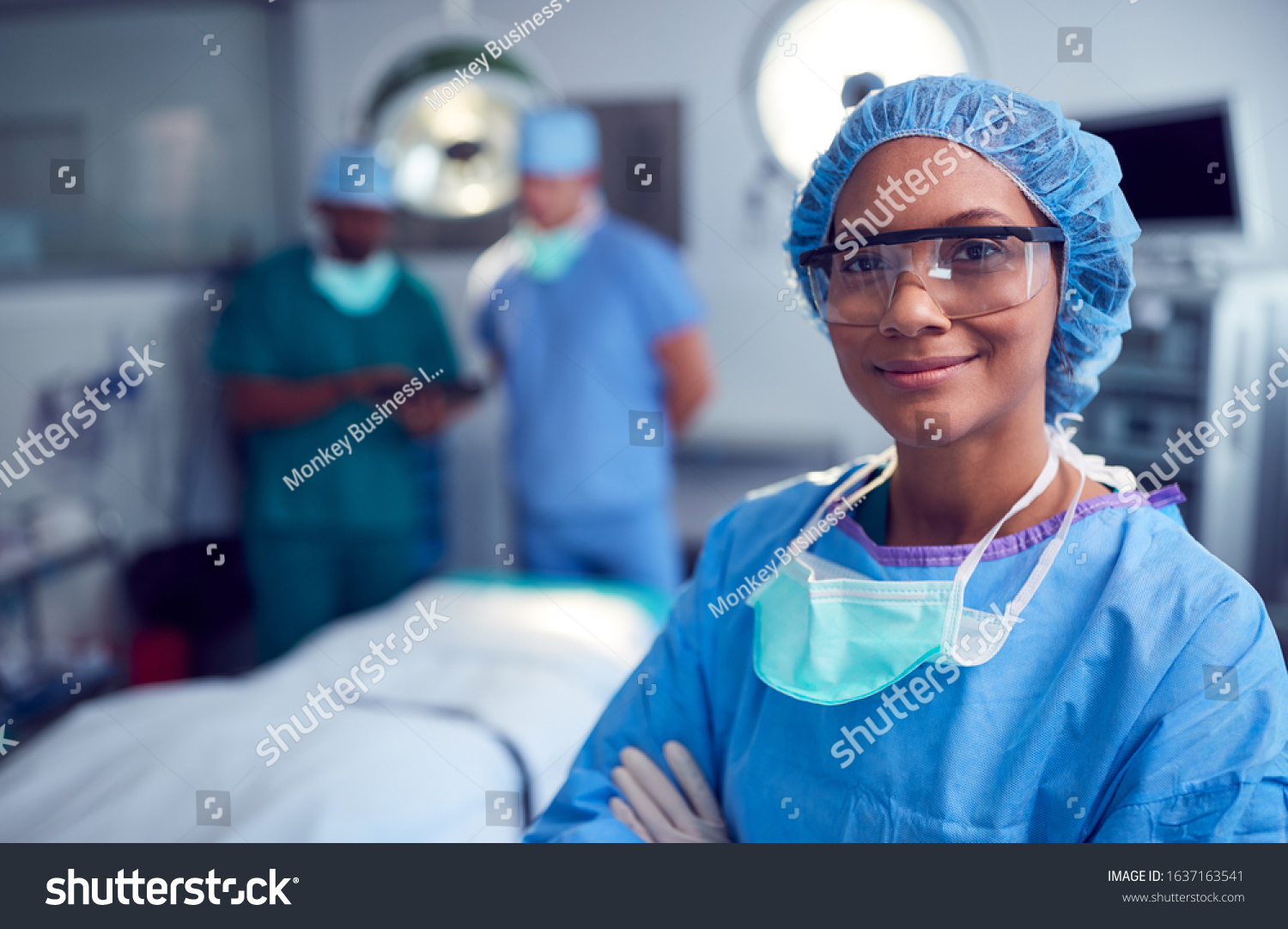 Portrait Of Female Surgeon Wearing Scrubs And Protective Glasses In Hospital Operating Theater #1637163541