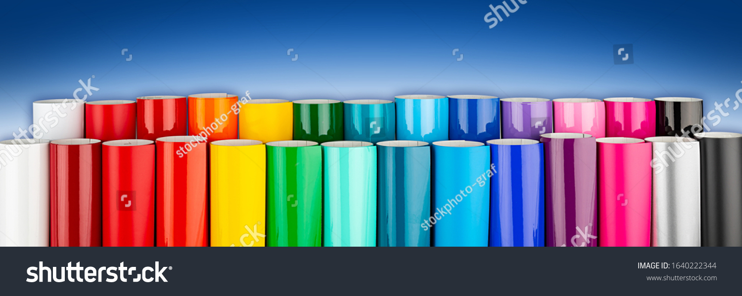 Row of various rainbow colored vinyl car wrapping or plotter cutting sticker foil film rolls on blue white wide panorama banner background #1640222344