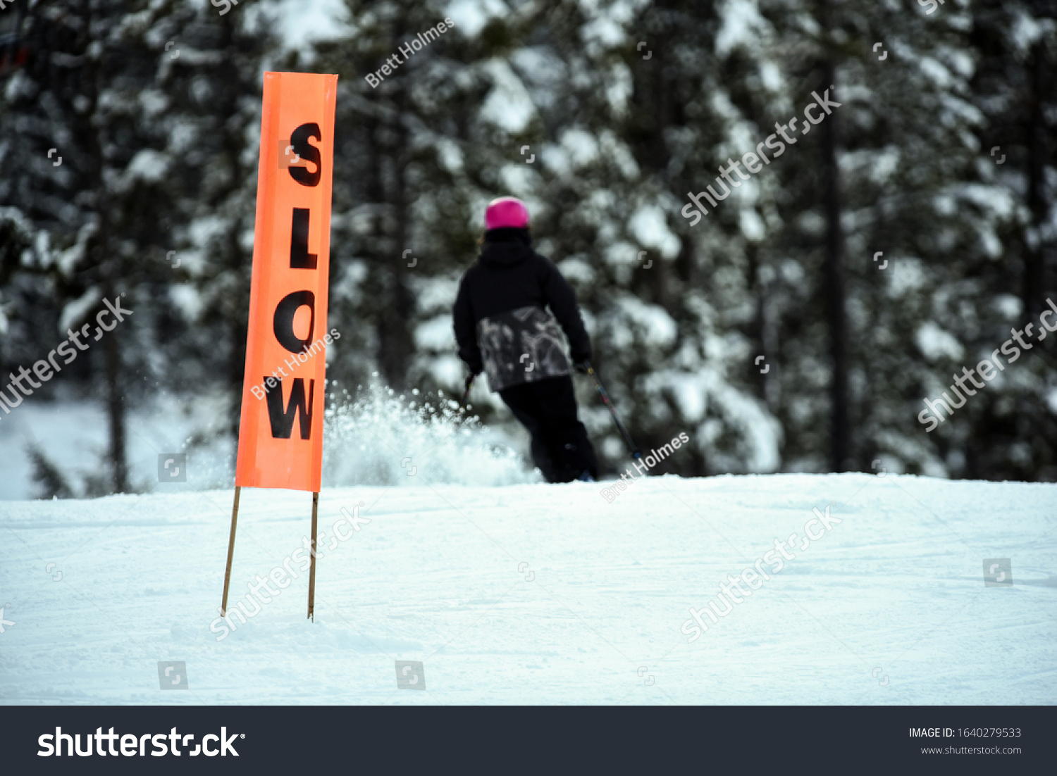 Orange slow caution sign with skier on downhill run #1640279533