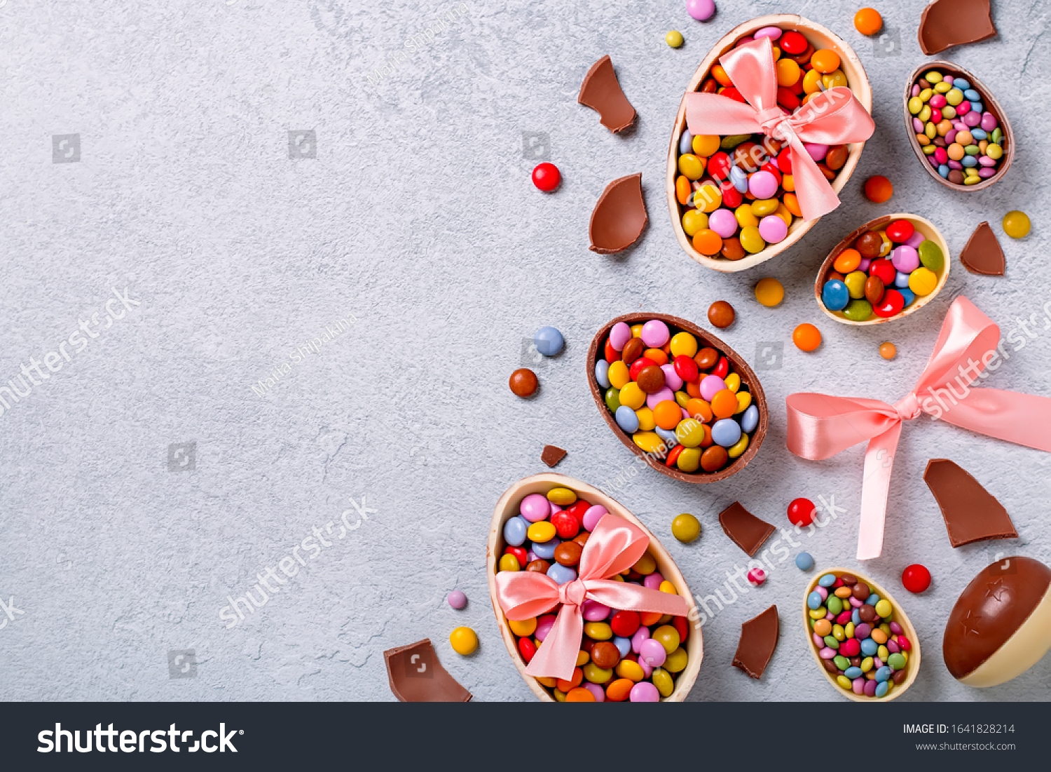 Chocolate Easter eggs and candy on concrete table, festive Easter background flat lay, copy space. Easter card with traditional treats on grey table top. Sweet Easter concept #1641828214