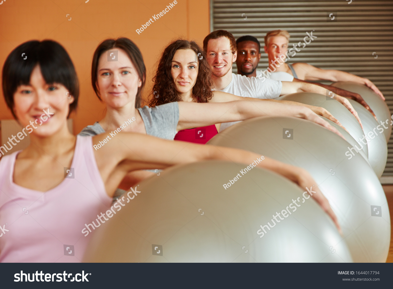 Group in fitness class doing exercise with exercise ball #1644017794