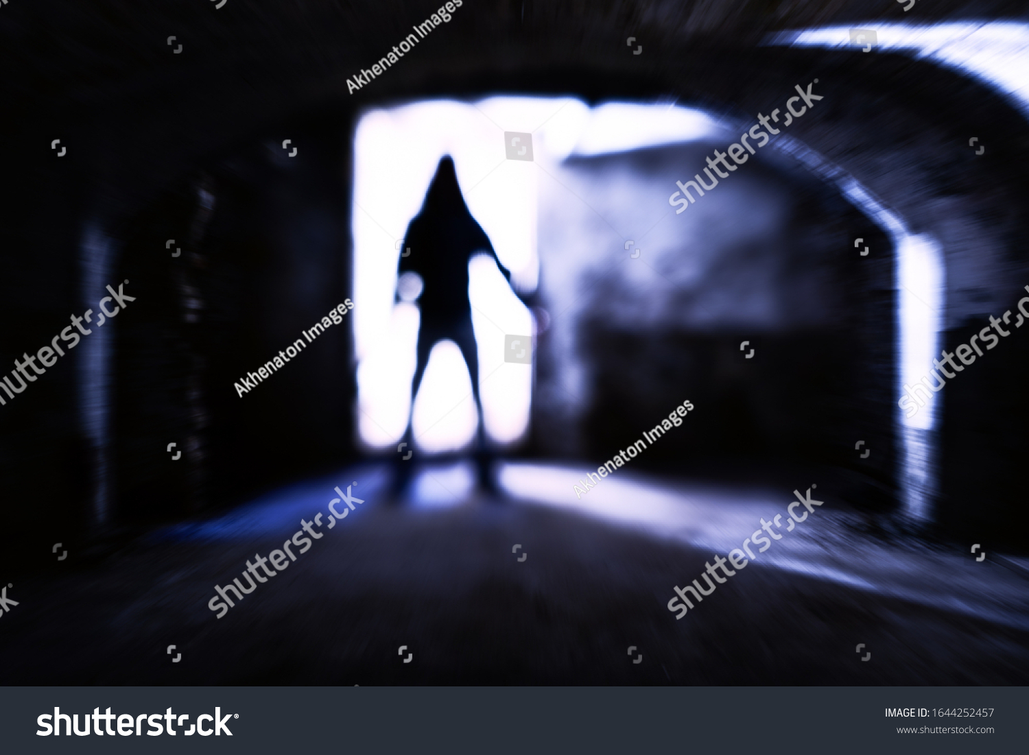Silhouette of evil theatening body in dark basement - Sinister figure standing at dungeon door with dangerous attitude - Concept of a dreadful encounter with blurred subject in backlight - Image #1644252457