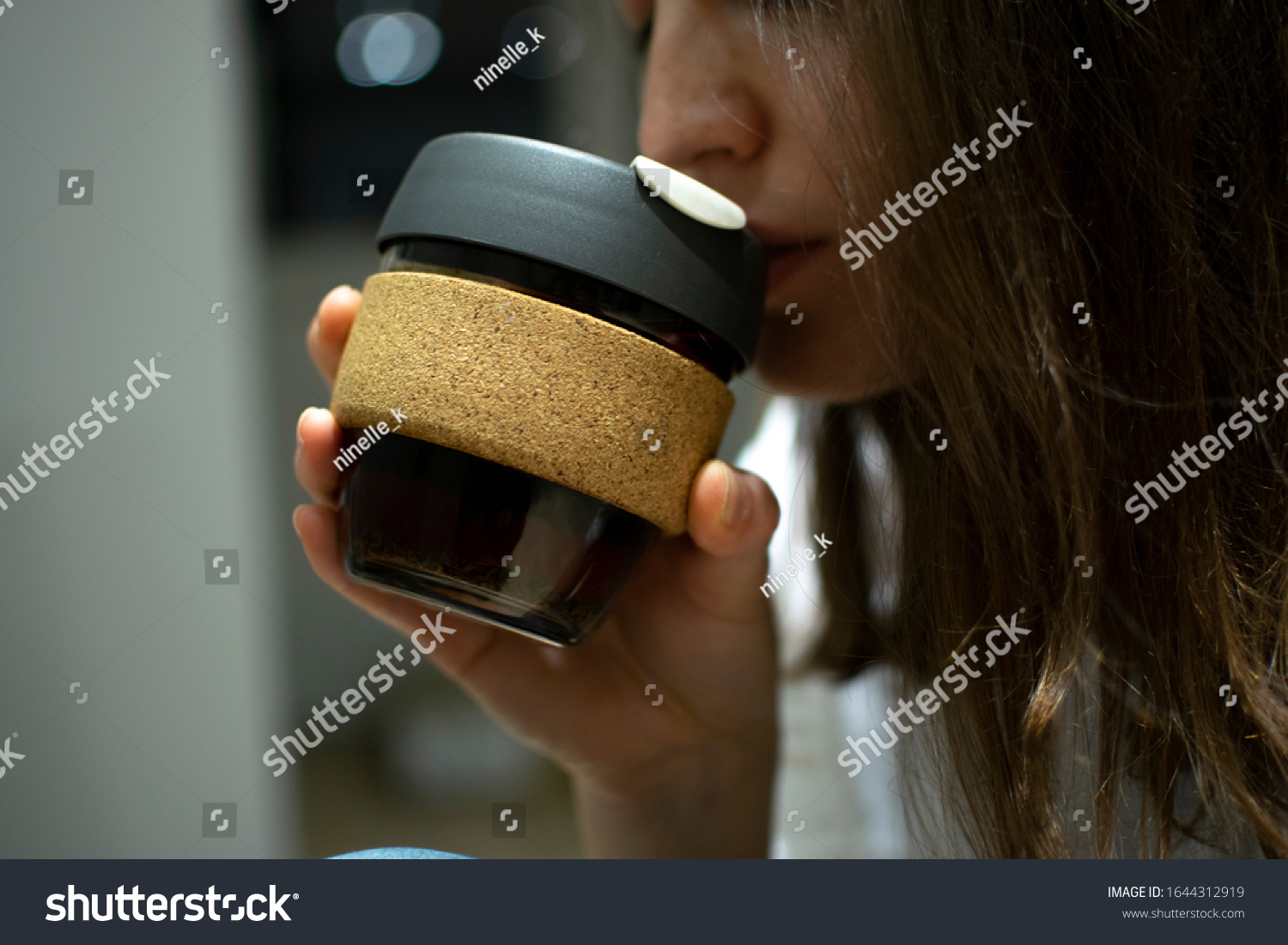 Reusable Coffee Eco Cup. Toughened Glass Cup & Natural Cork Band. Secure silicon lid. Friendly, Spill Proof Travel Mug with Lid | Black.A young girl drinks from a reusable cup. Keep Cup  #1644312919