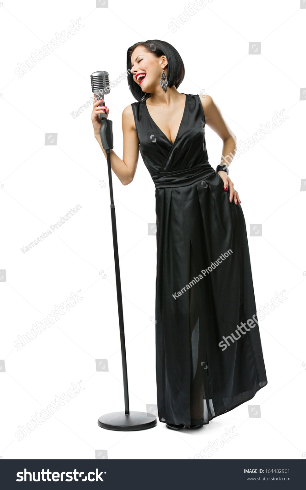 Full-length portrait of woman musician wearing long black evening dress and holding mic #164482961