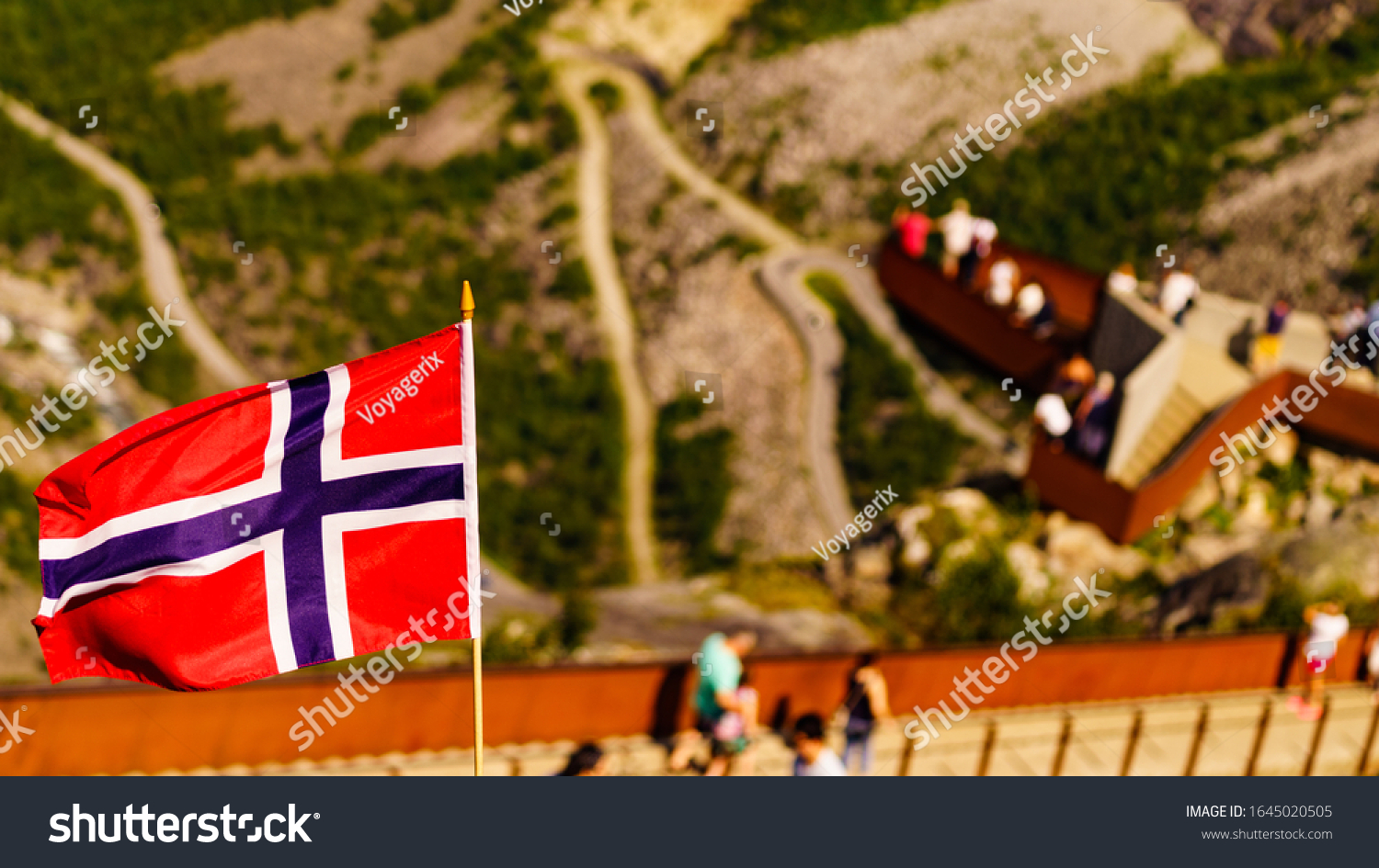 Trollstigen mountain road landscape in Norway, Europe. Norwegian flag waving and many tourists people on viewing platform in background. National tourist route. #1645020505