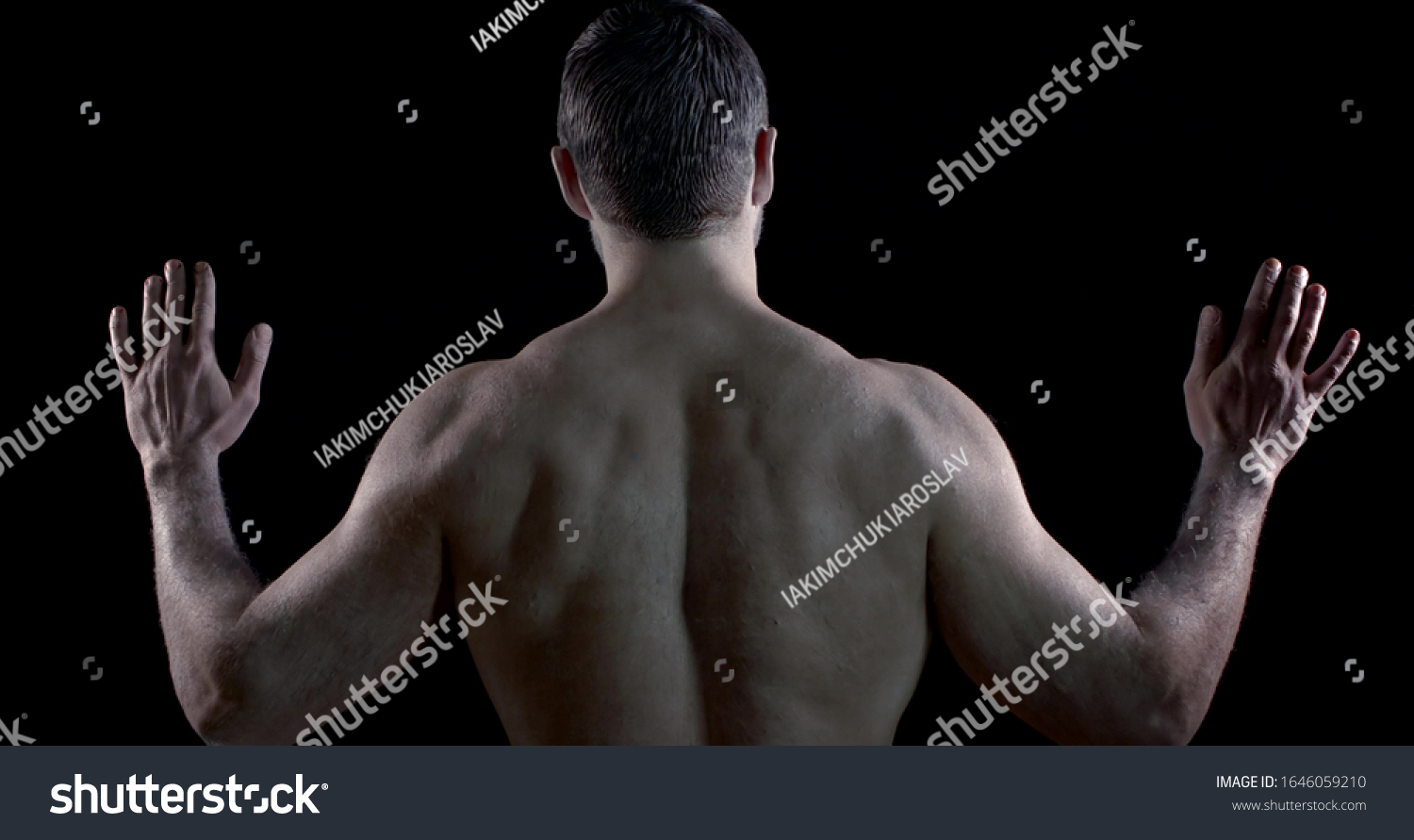 a brunette with pale skin poses with his back against a black background. he raises open palms to shoulder level and turns them, then head. the man turns and makes undulating movements with hands #1646059210