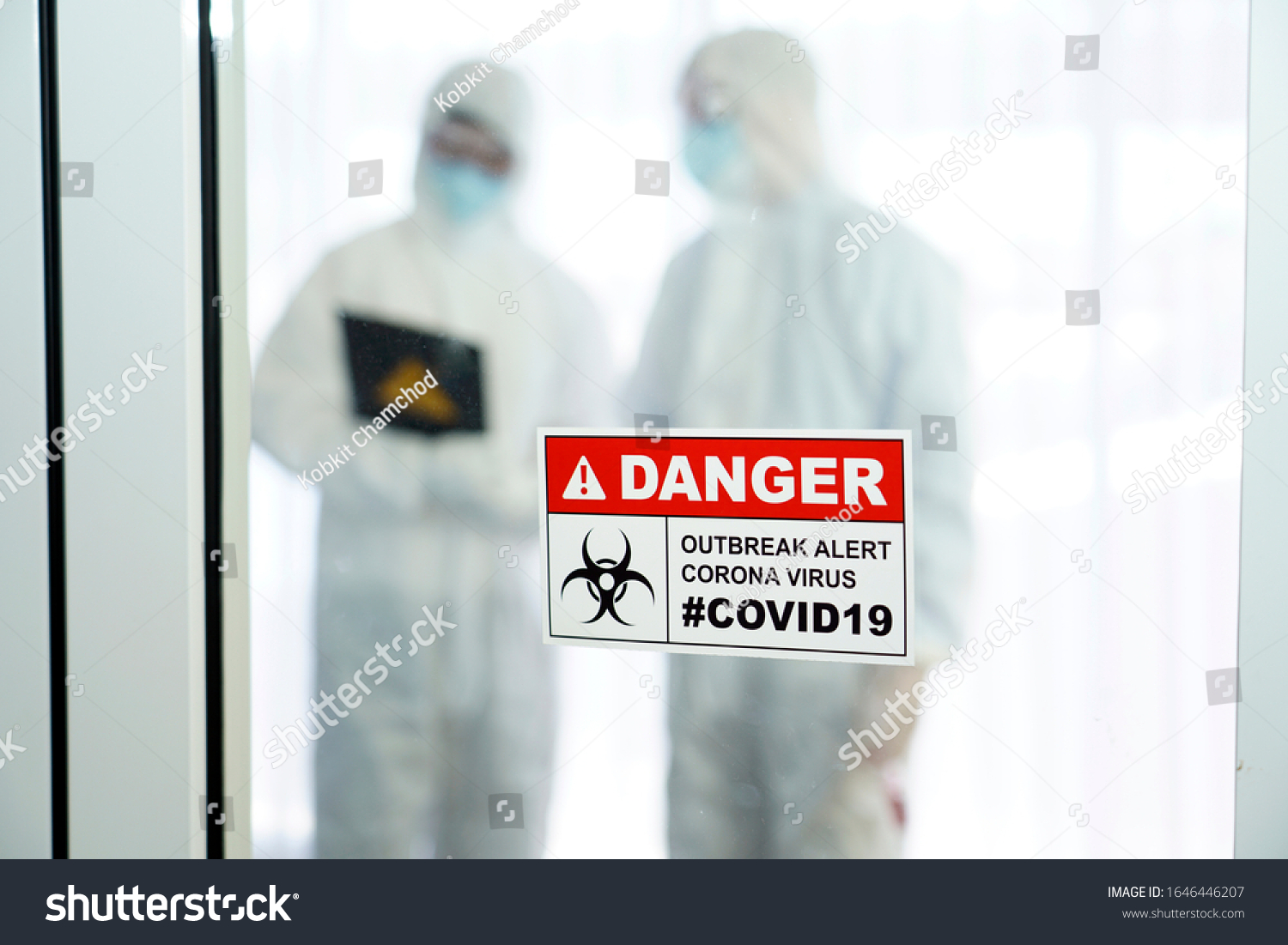 Outbreak alert Coronavirus COVID 19, COVID 19 signage in front of control area with doctors in personal protective equipment inside. #1646446207
