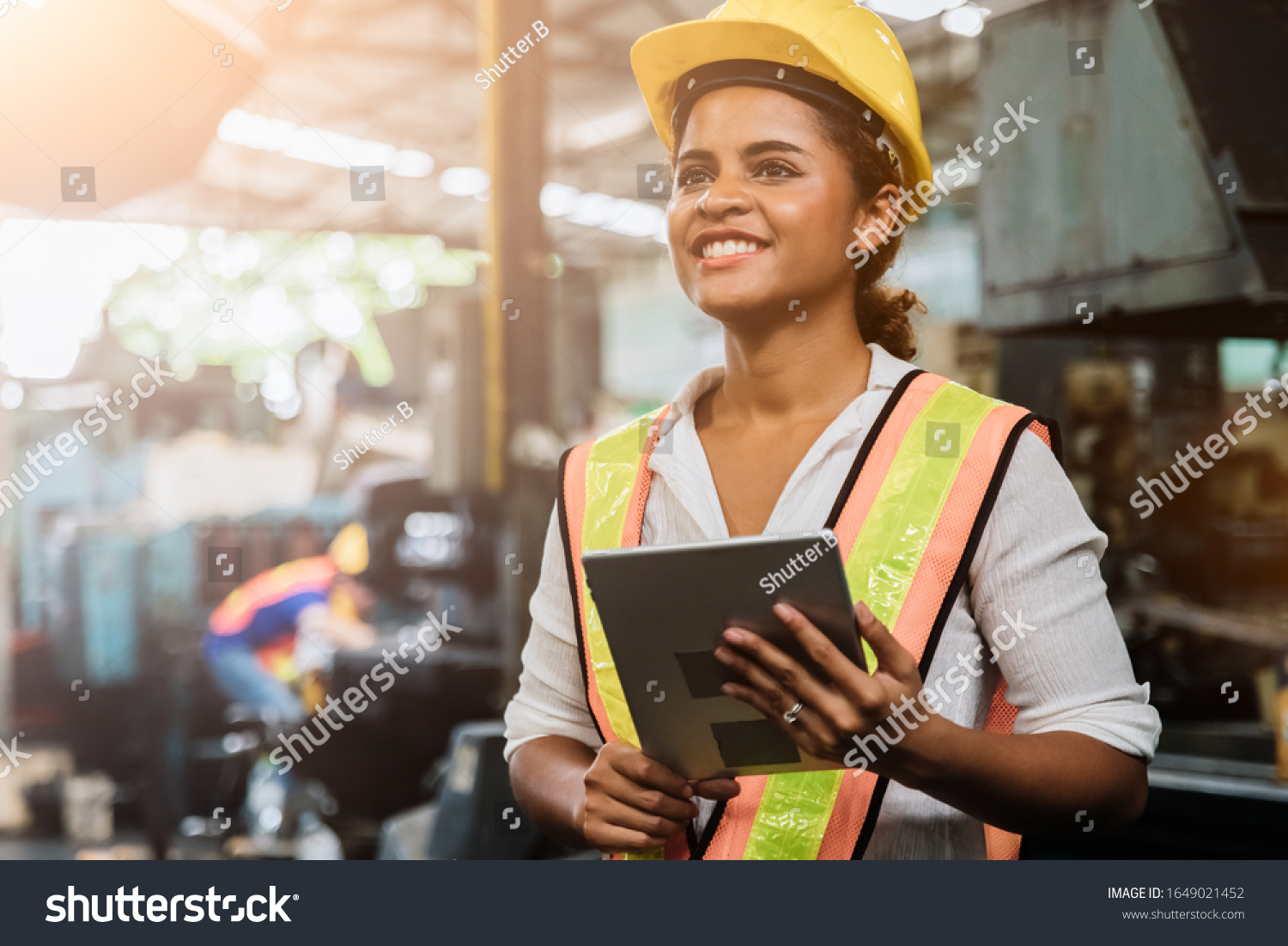 Industry maintenance engineer woman dark skin wearing uniform and safety helmet under inspection and checking production process on factory station by tablet. Industry, Engineer, construction concept. #1649021452