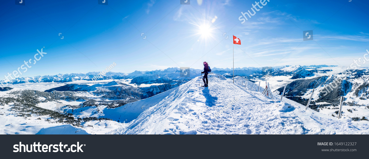winter sports: snow shoe hiker a the top of the snowy mountain in the swiss alps. panoramic picture of winter hiker at the top of the hill in switzerland. mountain panorama with sun and blue sky #1649122327