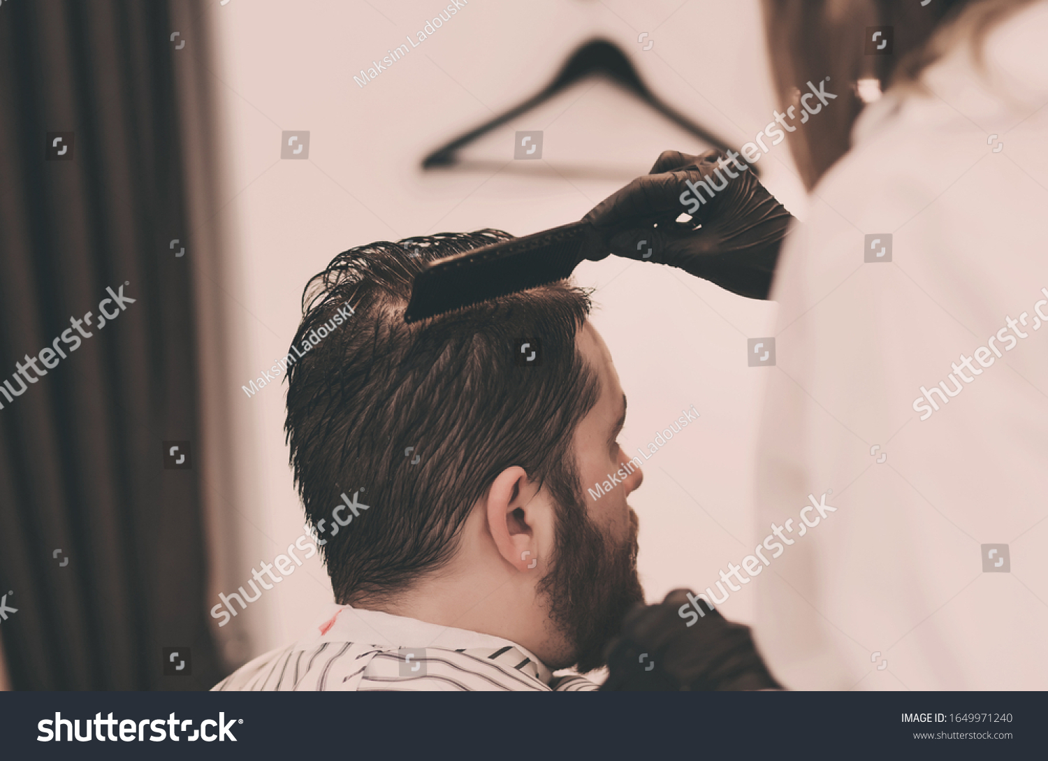 master combs the hair and beards of men in the Barber shop, the Barber makes a hairstyle for a bearded man #1649971240