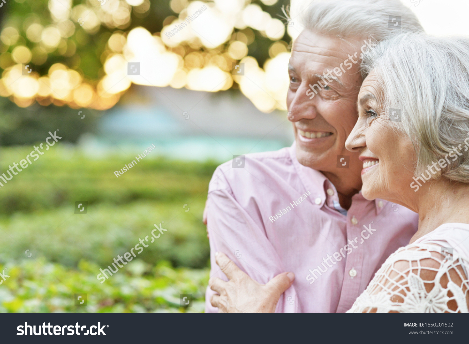 Close up portrait of smiling senior couple embracing in autumn park #1650201502