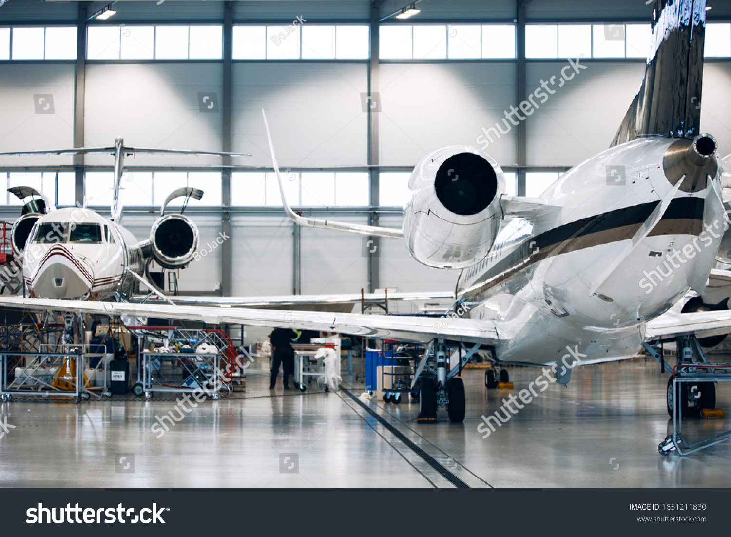 Maintenance of airplane in large white hangar. Modern private jet at the factory #1651211830