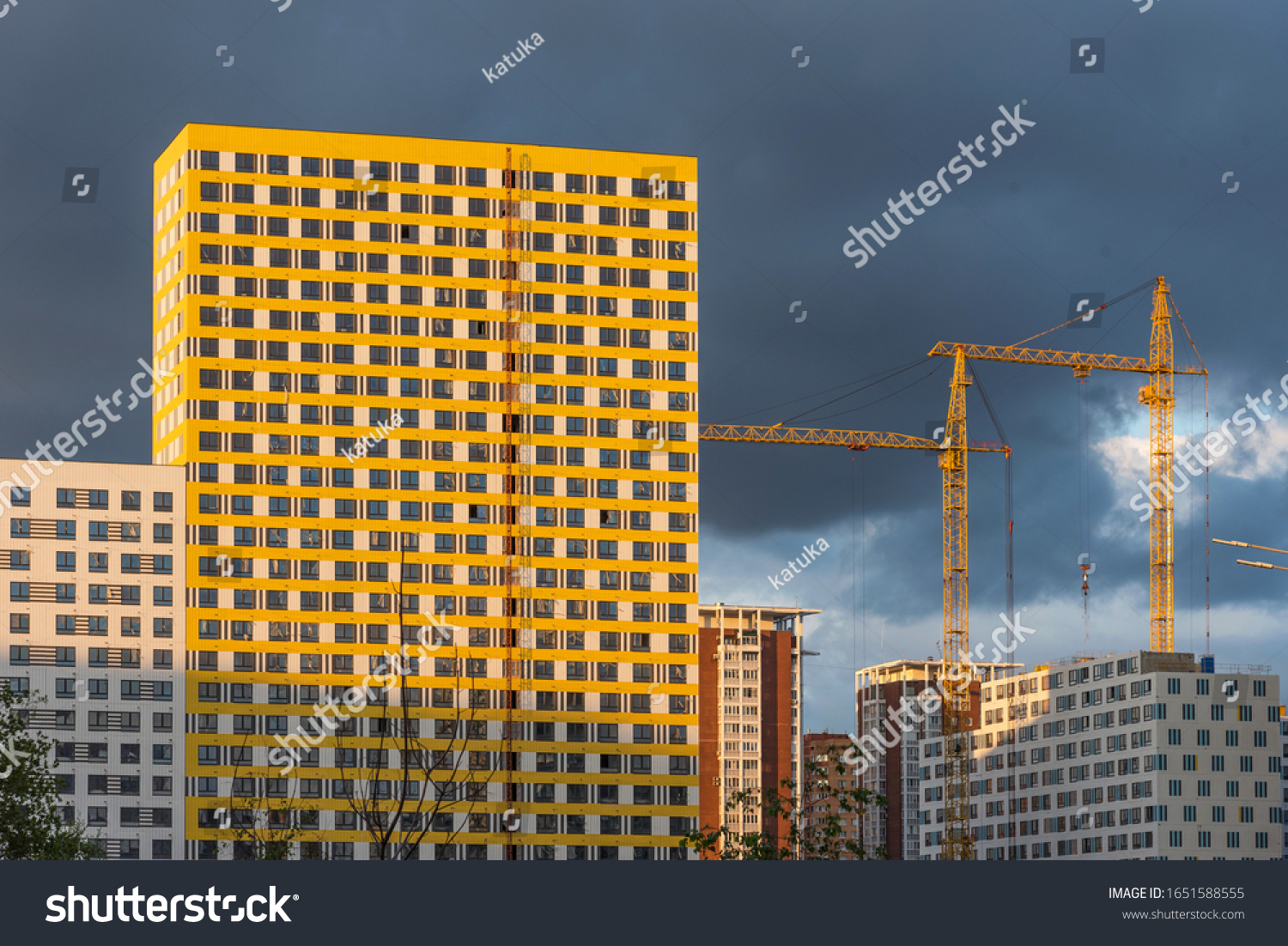 Construction in progress, construction of a modern new residential complex and cranes at sunset against a dramatic sky. Modern new residential complex. #1651588555