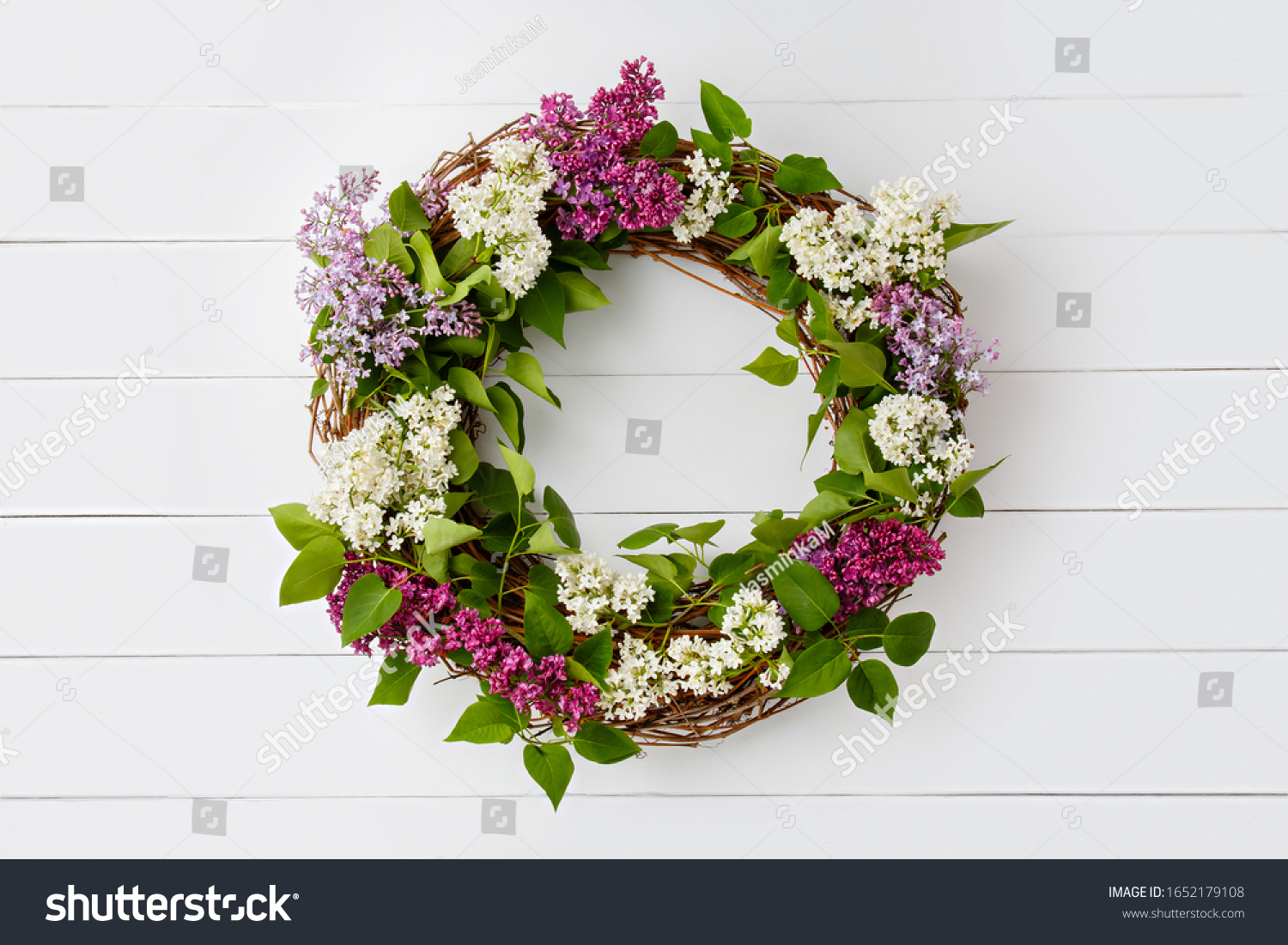 Wreath from purple lilac flowers on white wooden background. Surprise for lovely woman. Natural spring style. Aromatherapy.  Flowers Flat lay, top view. Background with copy space. Spring blossom mood #1652179108