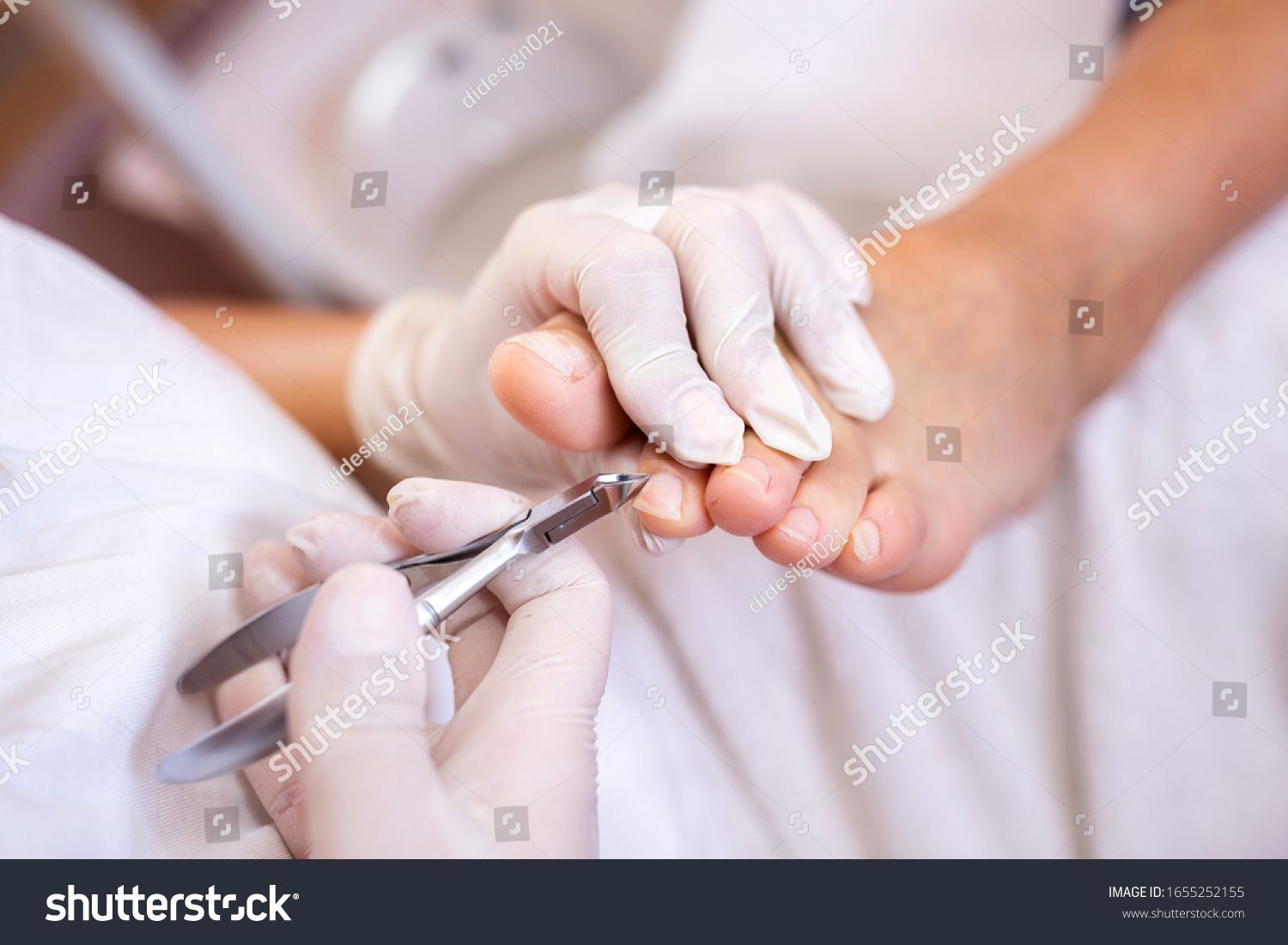Pedicure salon employee using nail nippers while trimming toe nails #1655252155
