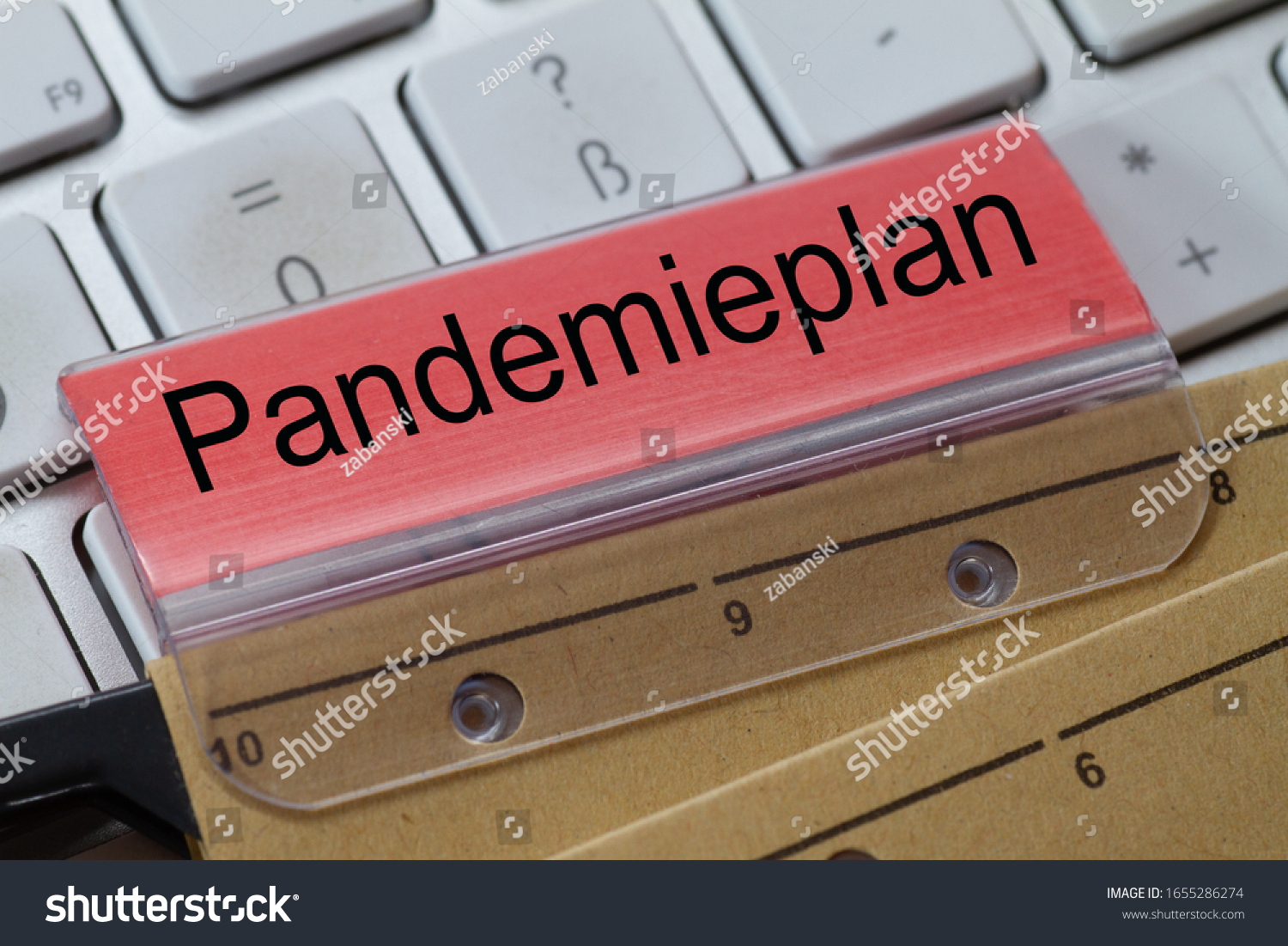 The German word for pandemic plan can be seen on the label of a brown hanging folder. The hanging folder is on a computer keyboard. #1655286274