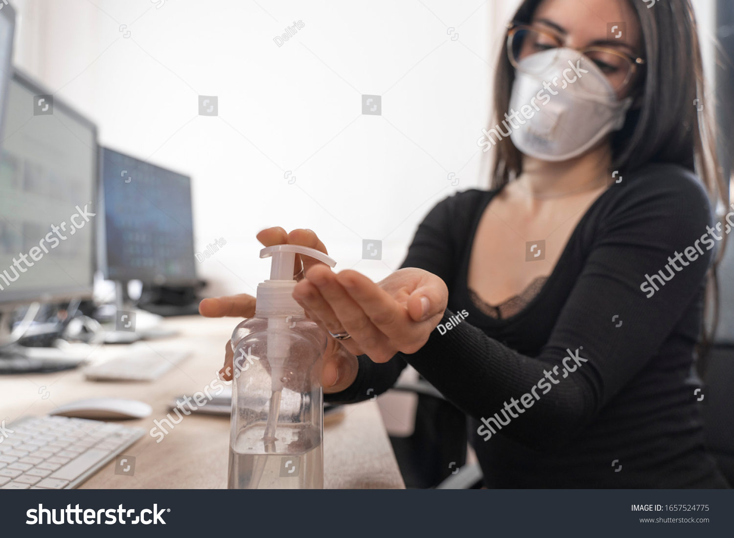 Corona Virus. Woman cleaning her hands at the office. Sick with mask for corona virus. Workplace desk with computer. Woman spraying alcohol gel or antibacterial soap sanitizer. #1657524775