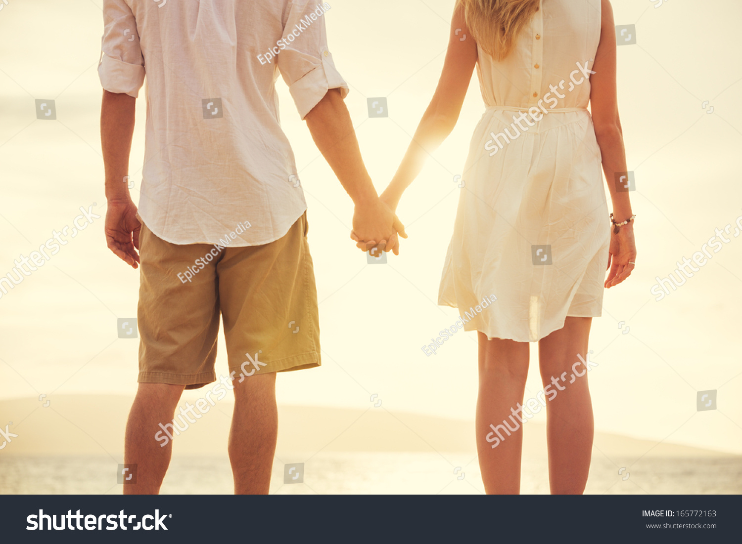 Young couple in love, Attractive man and woman enjoying romantic evening on the beach, Holding hands watching the sunset #165772163