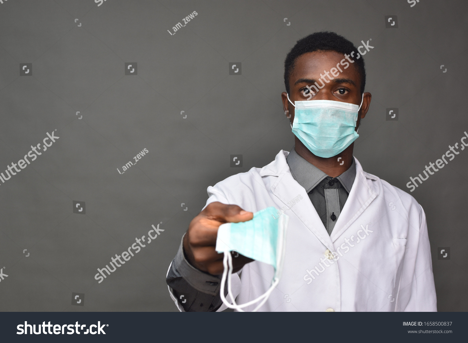 young black man in medical field, wearing a white coat and face mask, offering a face mask #1658500837