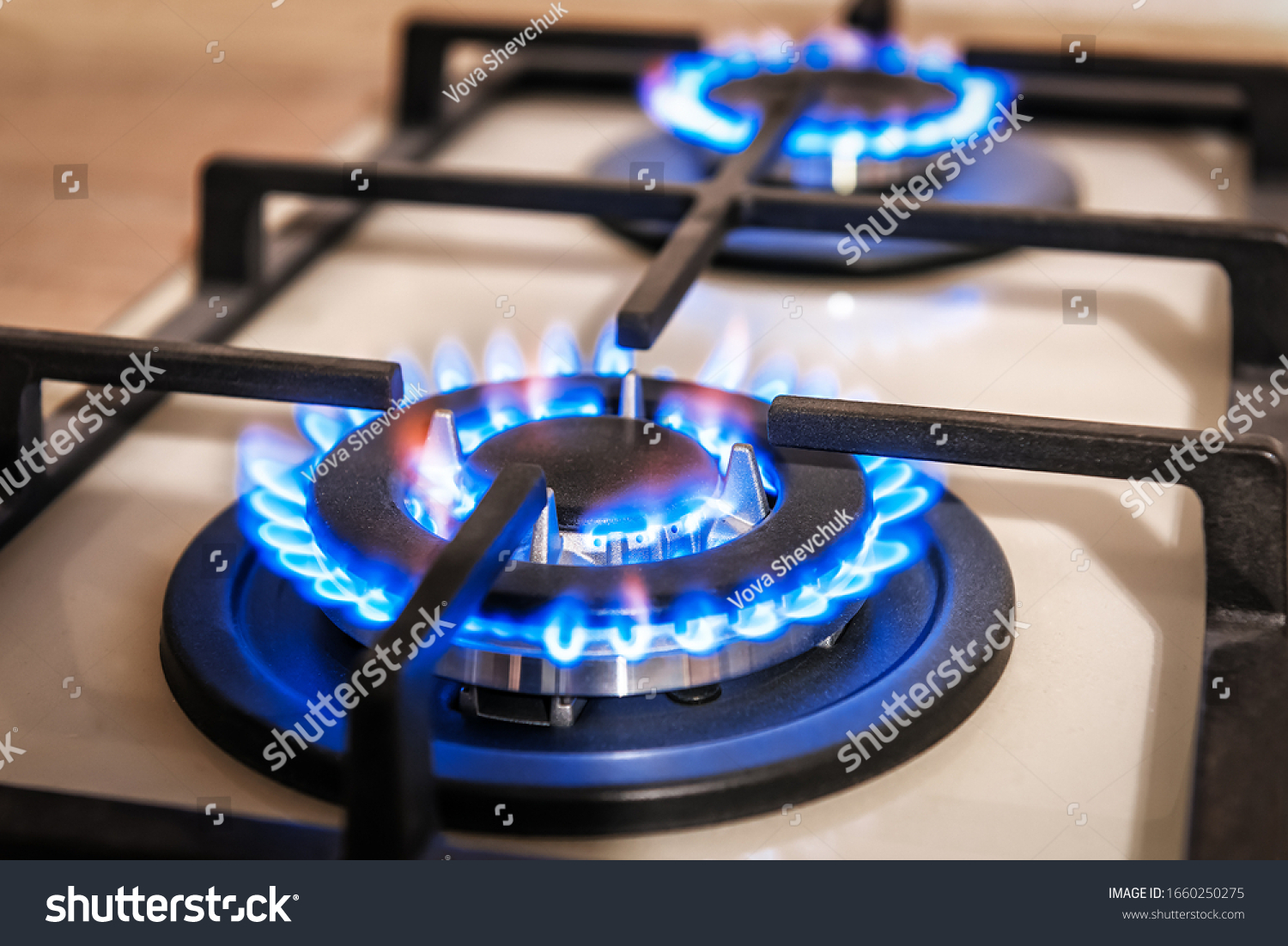 Closeup shot of blue fire from domestic kitchen stove top. Gas cooker with burning flames of propane gas. Industrial resources and economy concept. #1660250275