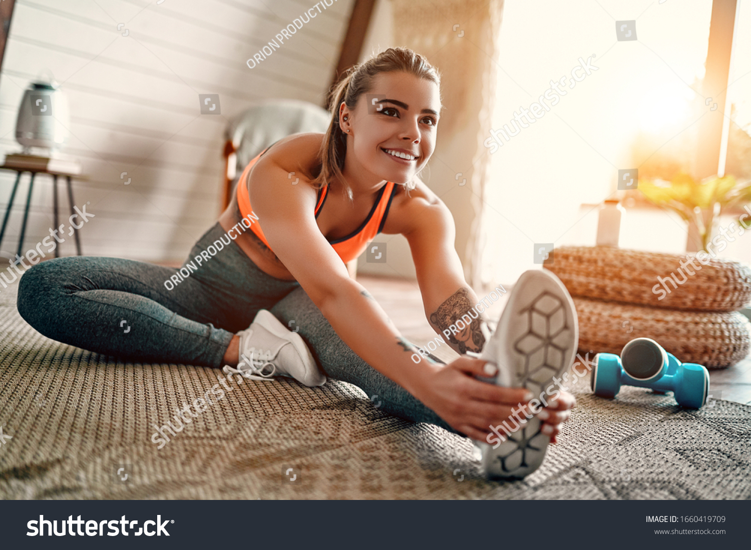 Athletic woman in sportswear doing fitness stretching exercises at home in the living room. Sport and recreation concept. #1660419709