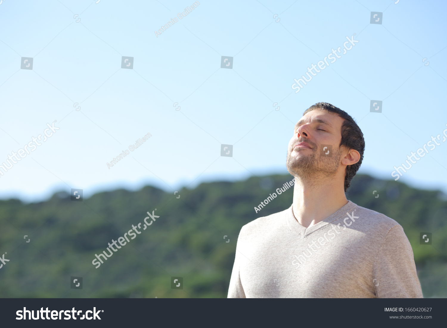 Relaxed man breathing fresh air near the mountains with a blue sky in the background #1660420627