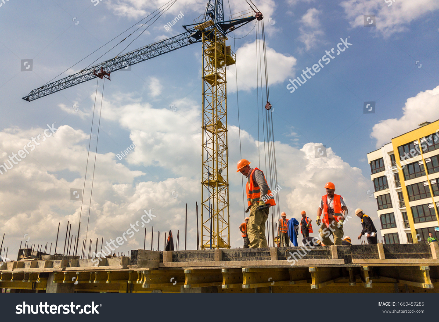 Kyiv, Ukraine - May 3, 2019: Workers working on concrete frame of tall apartment building under construction in a city. #1660459285