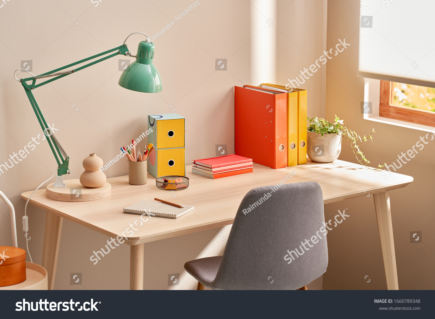 Chair placed near table with lamp and colorful stationery in cozy home office in morning #1660789348