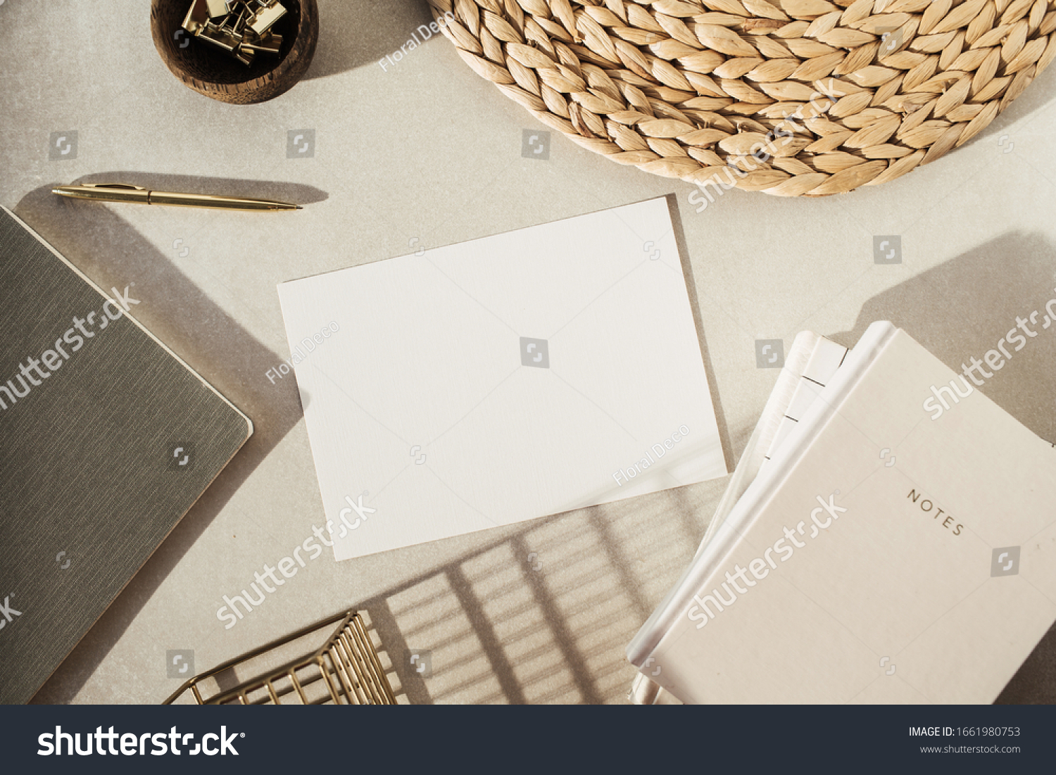 Flatlay blank paper sheet, notebooks, clips in wooden bowl, straw stand on beige concrete background. Home office desk workspace. Business, work template. Flat lay, top view. #1661980753