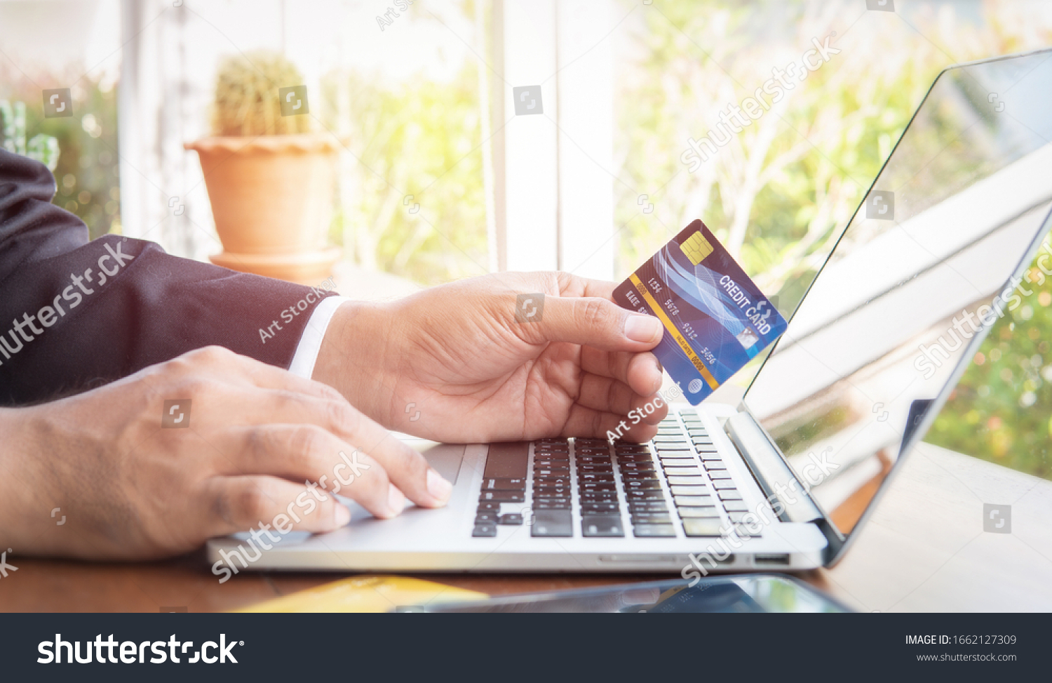 Business man hand hold credit card to shopping online on laptop computer, Debits saving purchase buy on table background. People contactless pay money in cashier, Person bank smart payment concept #1662127309