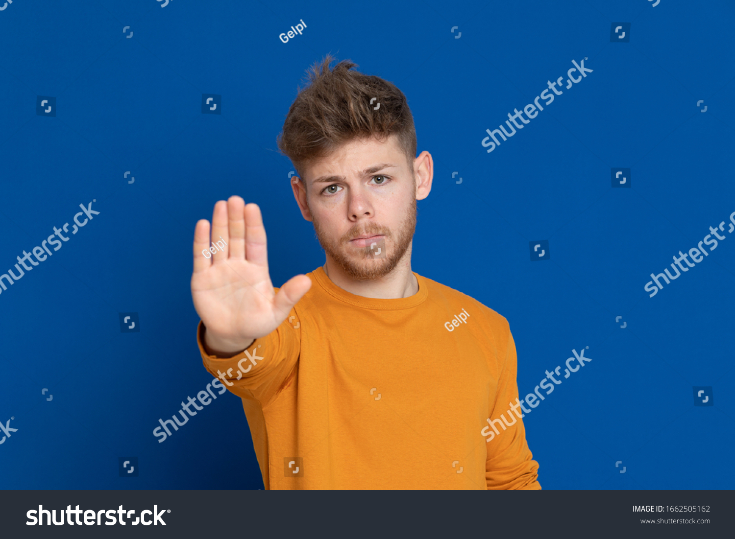 Attractive young guy with a yellow T-shirt on a blue background #1662505162