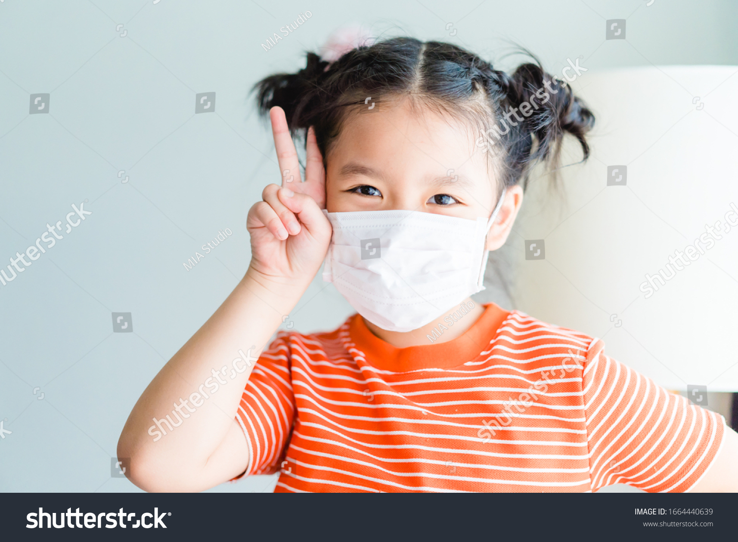 Coronavirus and Air pollution pm2.5 concept.Little chinese girl wearing mask for quarantine and show fighting gesture with Covid-19 virus outbreak.Wuhan coronavirus and epidemic virus symptoms. #1664440639