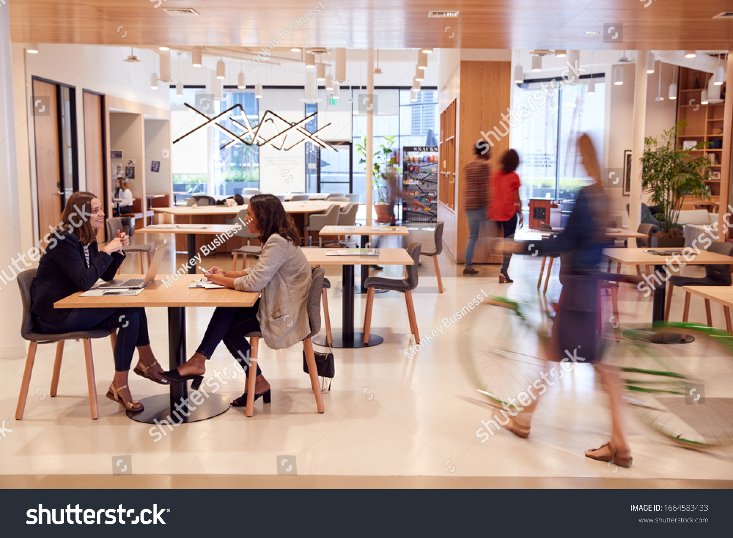 Interior Of Modern Open Plan Office With People Working And Commuters Arriving On Bikes #1664583433