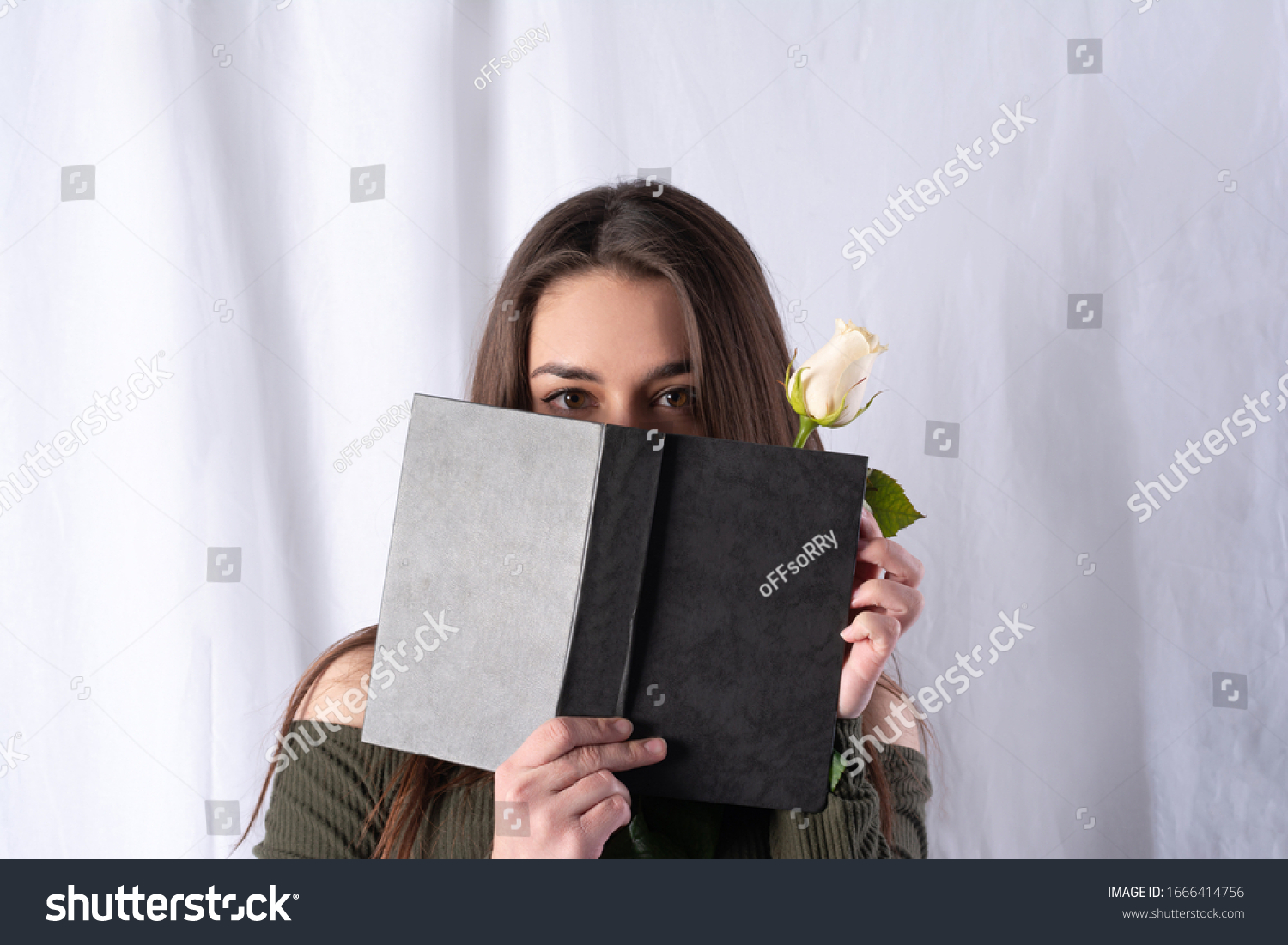 studio portrait of a girl. covered half of her face with a book with a dark cover. a white rose is seen from the book. concept art of intrigue and interest. fabric white fo
 #1666414756