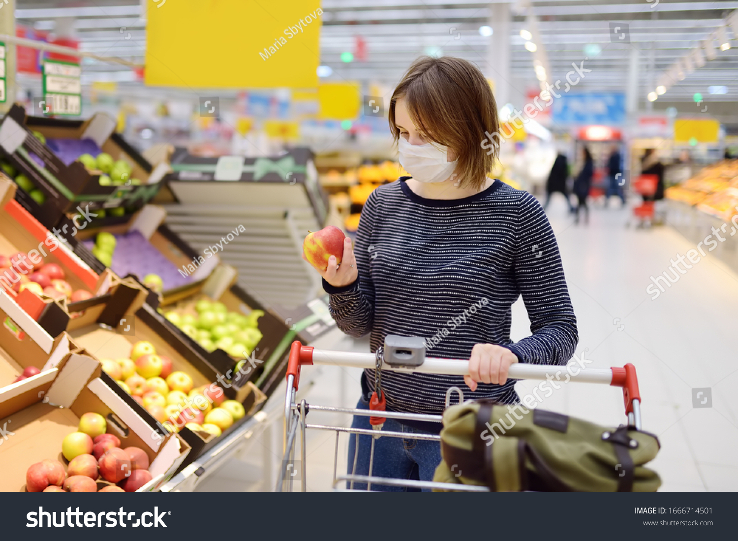 Young woman wearing disposable medical mask shopping in supermarket during coronavirus pneumonia outbreak. Protection and prevent measures while epidemic time. #1666714501