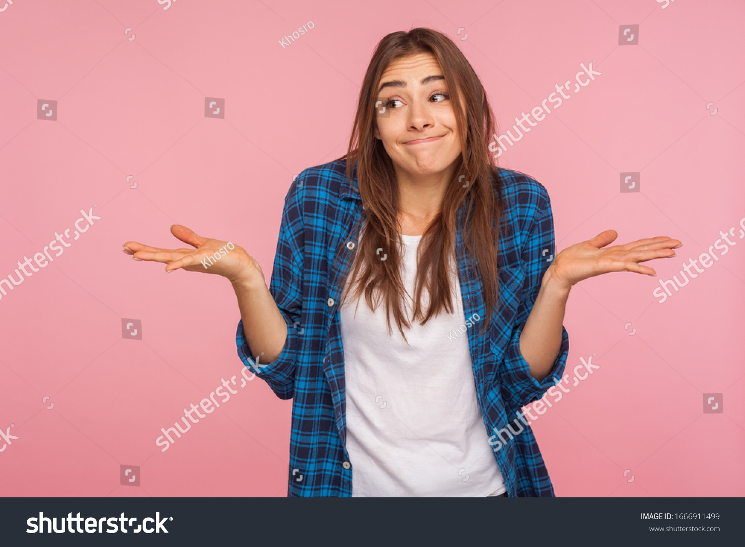 Don't know answer! Portrait of funny confused girl in checkered shirt shrugging shoulders with clueless embarrassed expression, having doubts, not sure. indoor studio shot isolated on pink background #1666911499