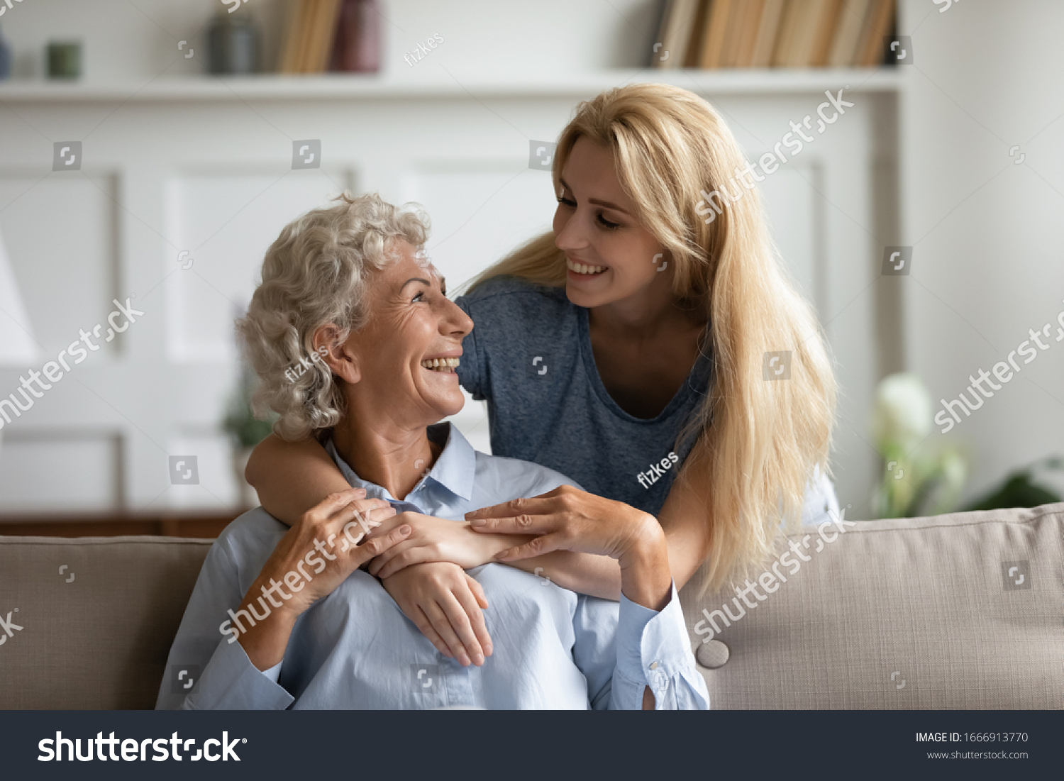 Overjoyed senior 60s mother and adult daughter relax together in living room hugging and cuddling, happy mature mum and grownup girl embrace show love enjoy home family weekend together #1666913770